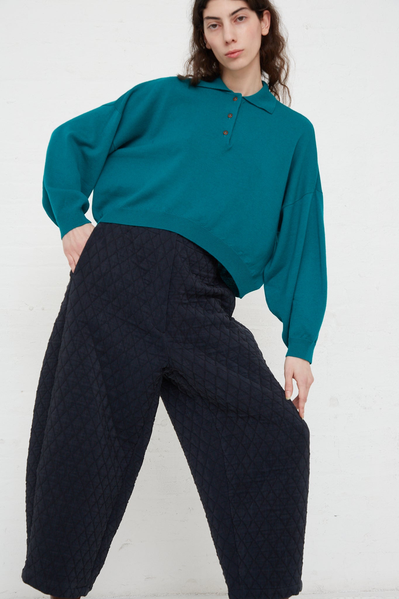 The model is wearing a teal sweater and Cordera's Quilted Curved Pant in Black with an elasticated waist.