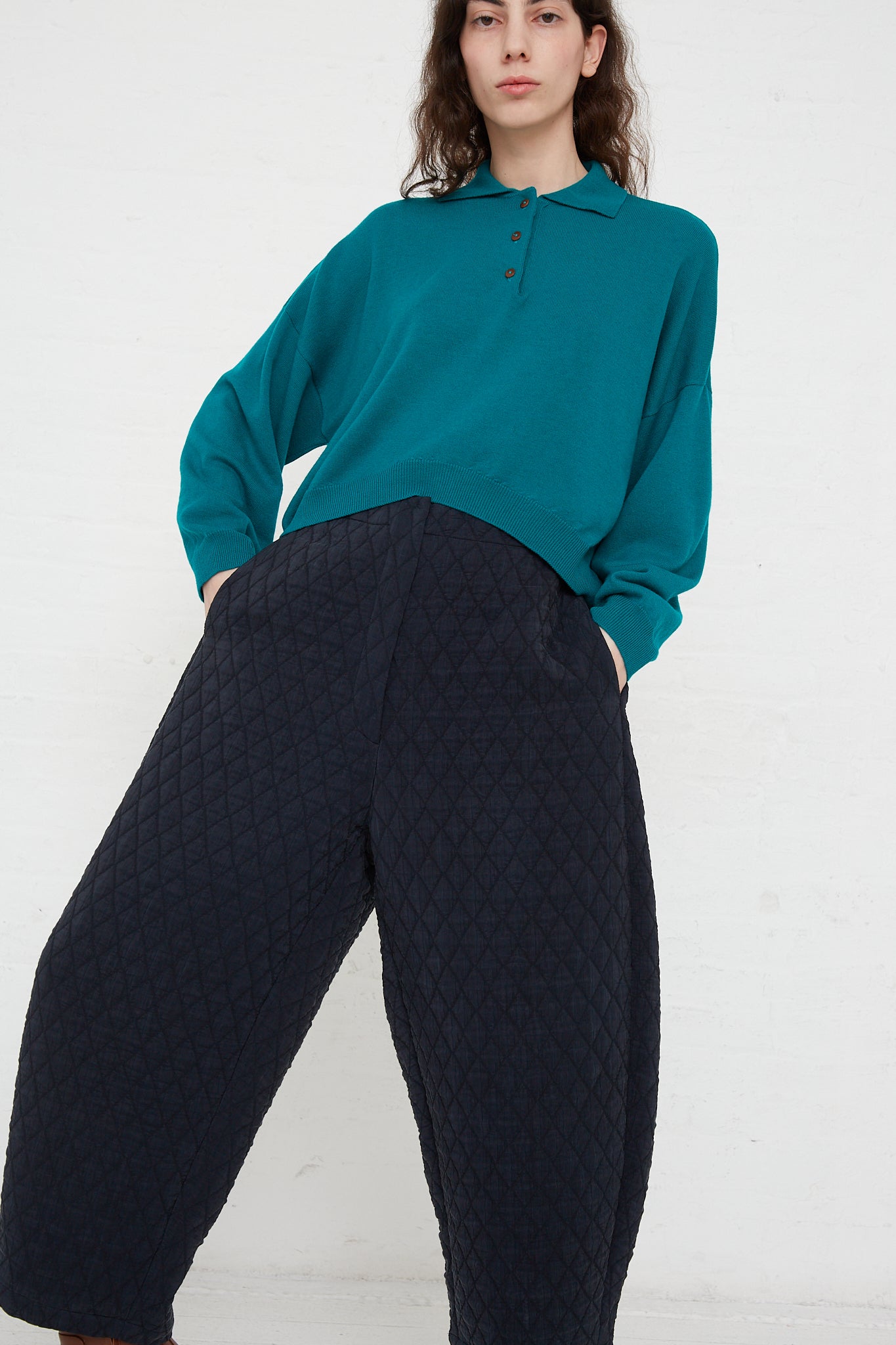 A model wearing a teal sweater with Cordera's Quilted Curved Pant in Black featuring an elasticated waist.