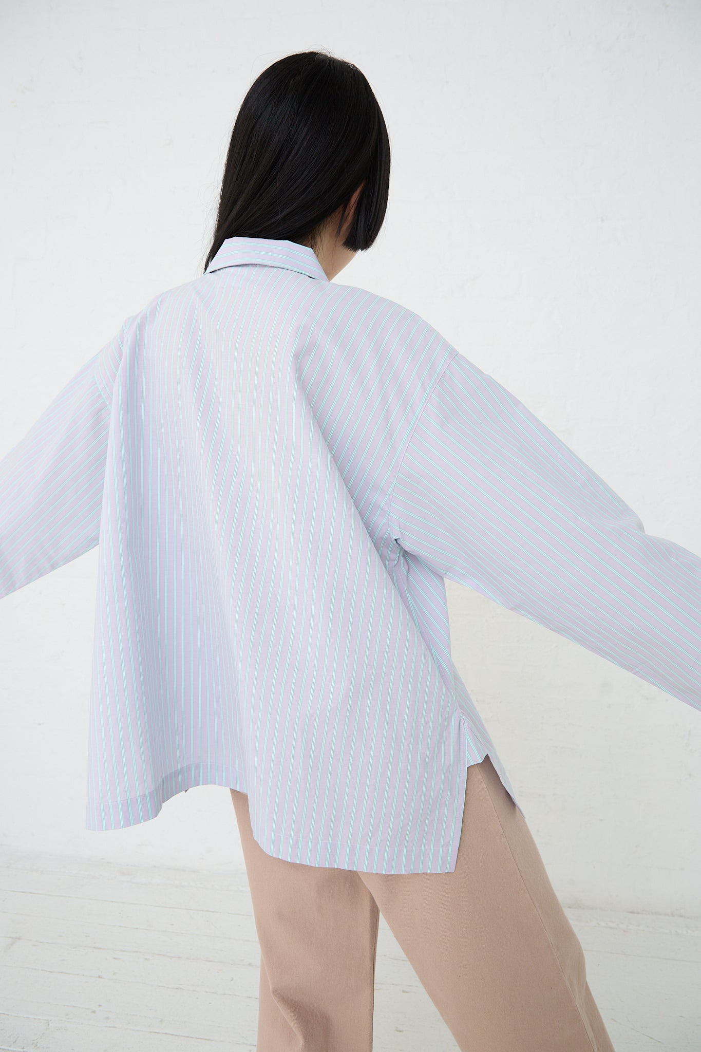 A sustainable woman's button-down shirt, made with Giza Cotton Kolla fabric, in a Lilac Stripe color scheme by Baserange. Back view and full length.