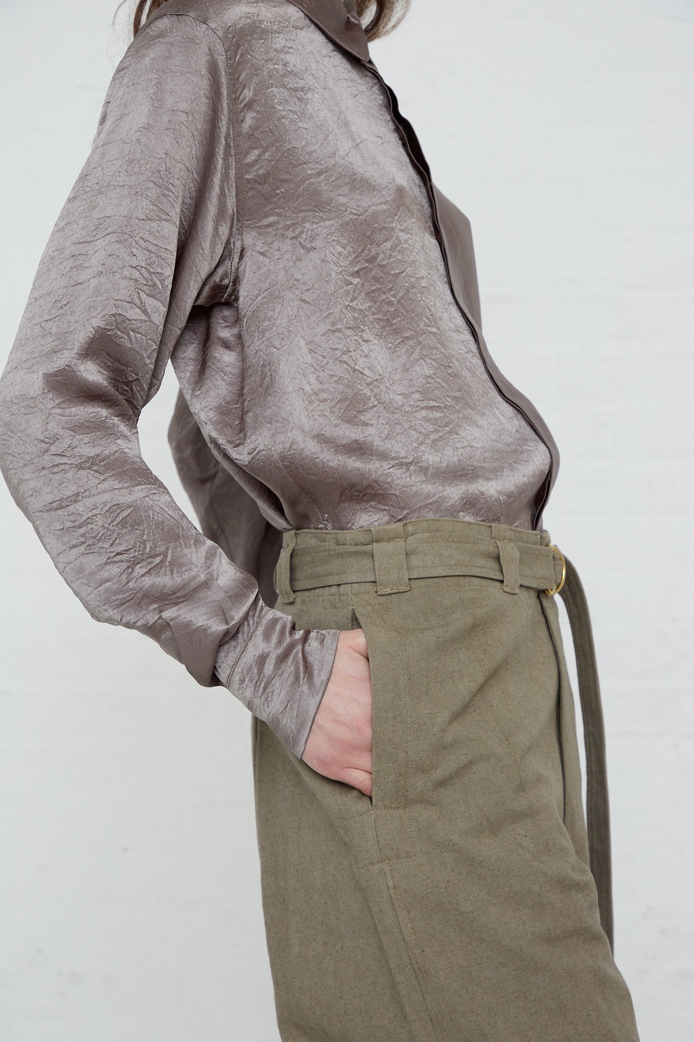 A woman wearing a grey shirt and olive pants made of the Belted Trouser in Fatigue by Lauren Manoogian, a cotton linen blend.