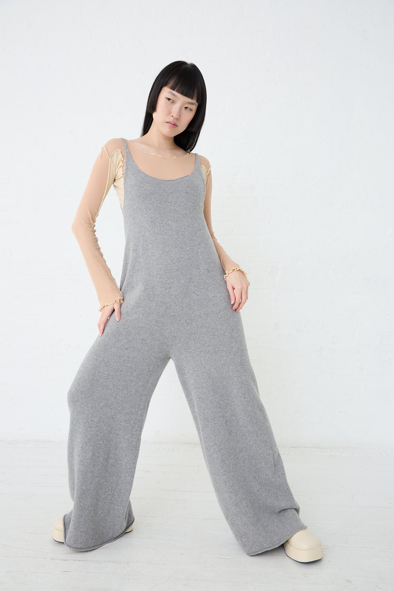A woman is posing in a Baserange Recycled Cashmere Rim Tank Jumpsuit in Grey Melange.