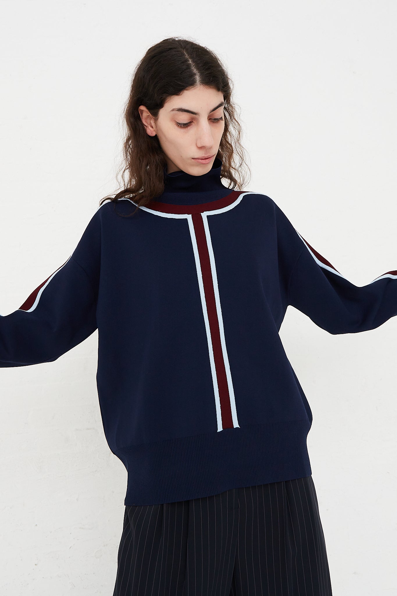 A model wearing a Track Stripe Mockneck Sweater in Midnight designed by Nomia brand.
