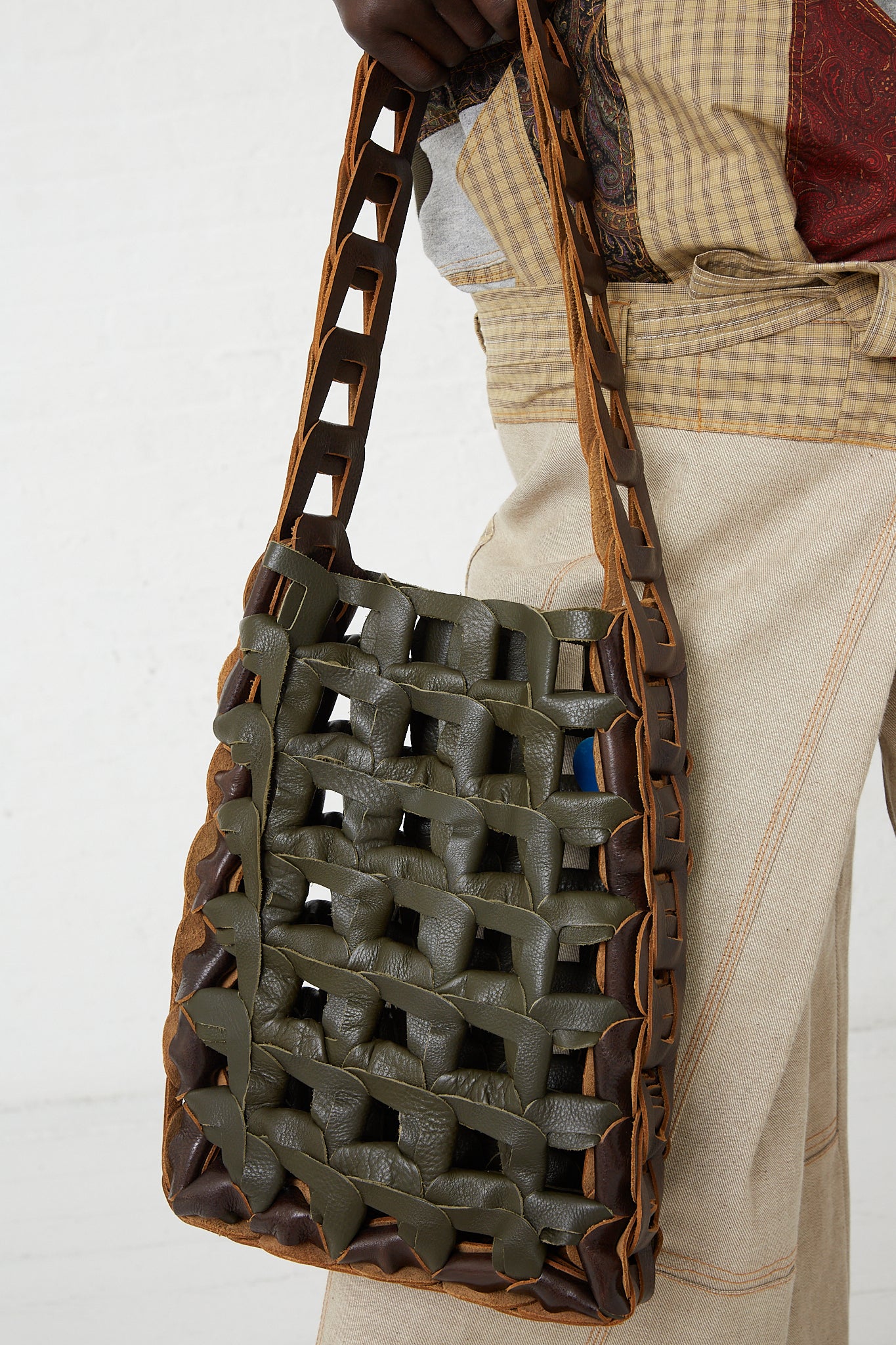 A woman is holding a SC103 Leather Medium Links Tote in Herb.