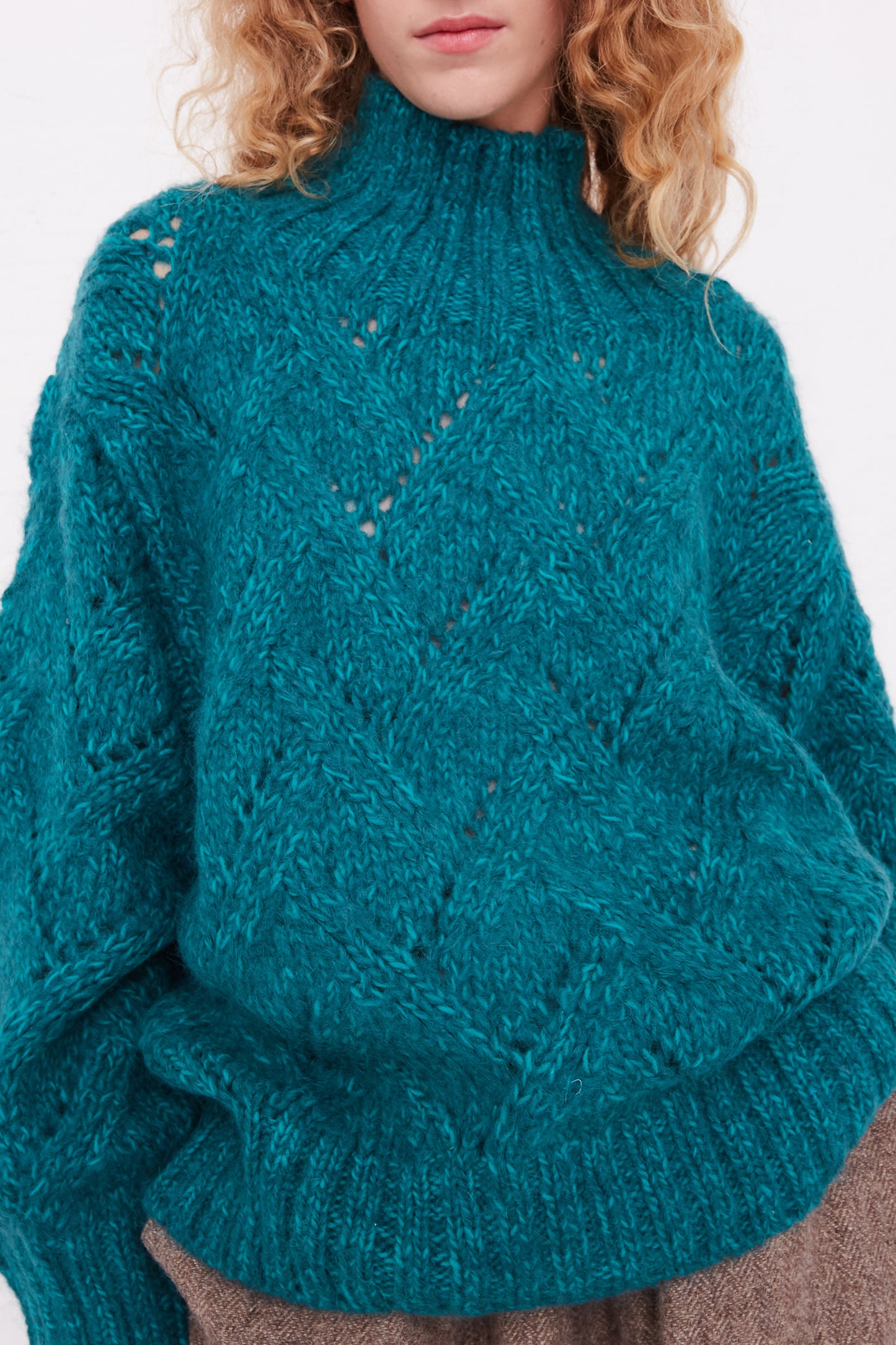 A woman wearing an oversized Hand-Knit Turtleneck in Green Teal sweater by Ichi Antiquités.