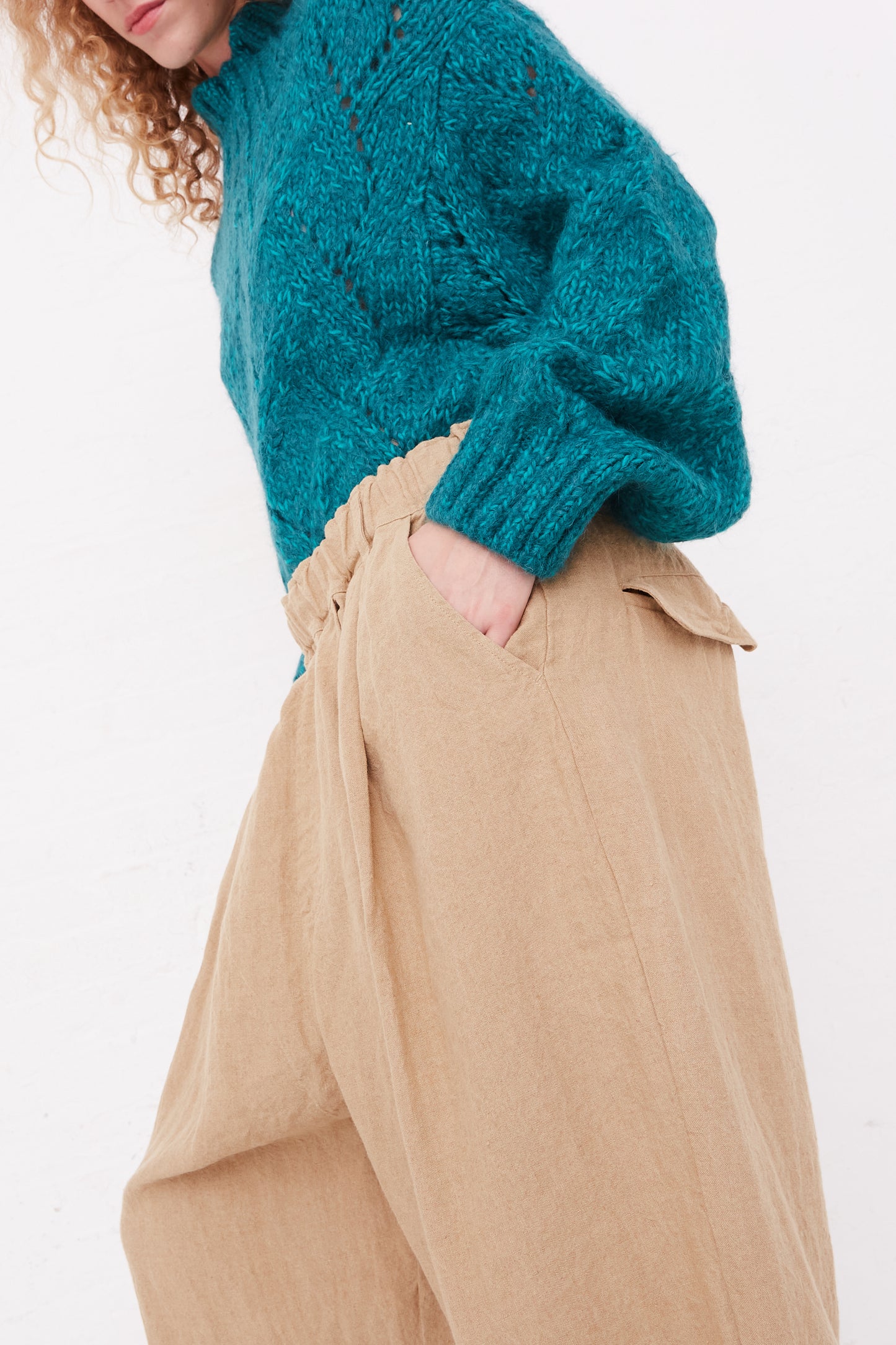 A model wearing Ichi Antiquités relaxed fit linen canvas pants in beige with an elasticated waist, paired with a teal sweater.