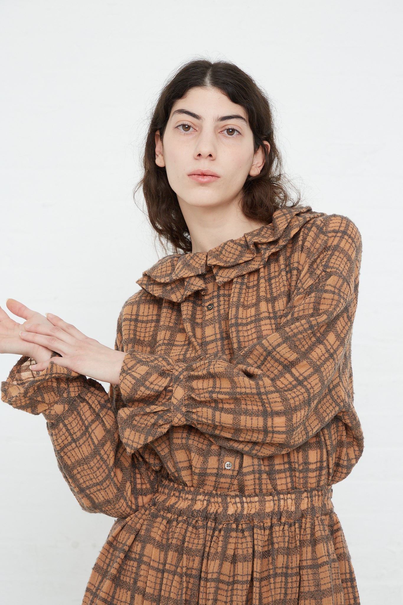 A woman in a relaxed fit Ichi Antiquités Wool Check Frill Blouse in Terracotta is posing for a photo.