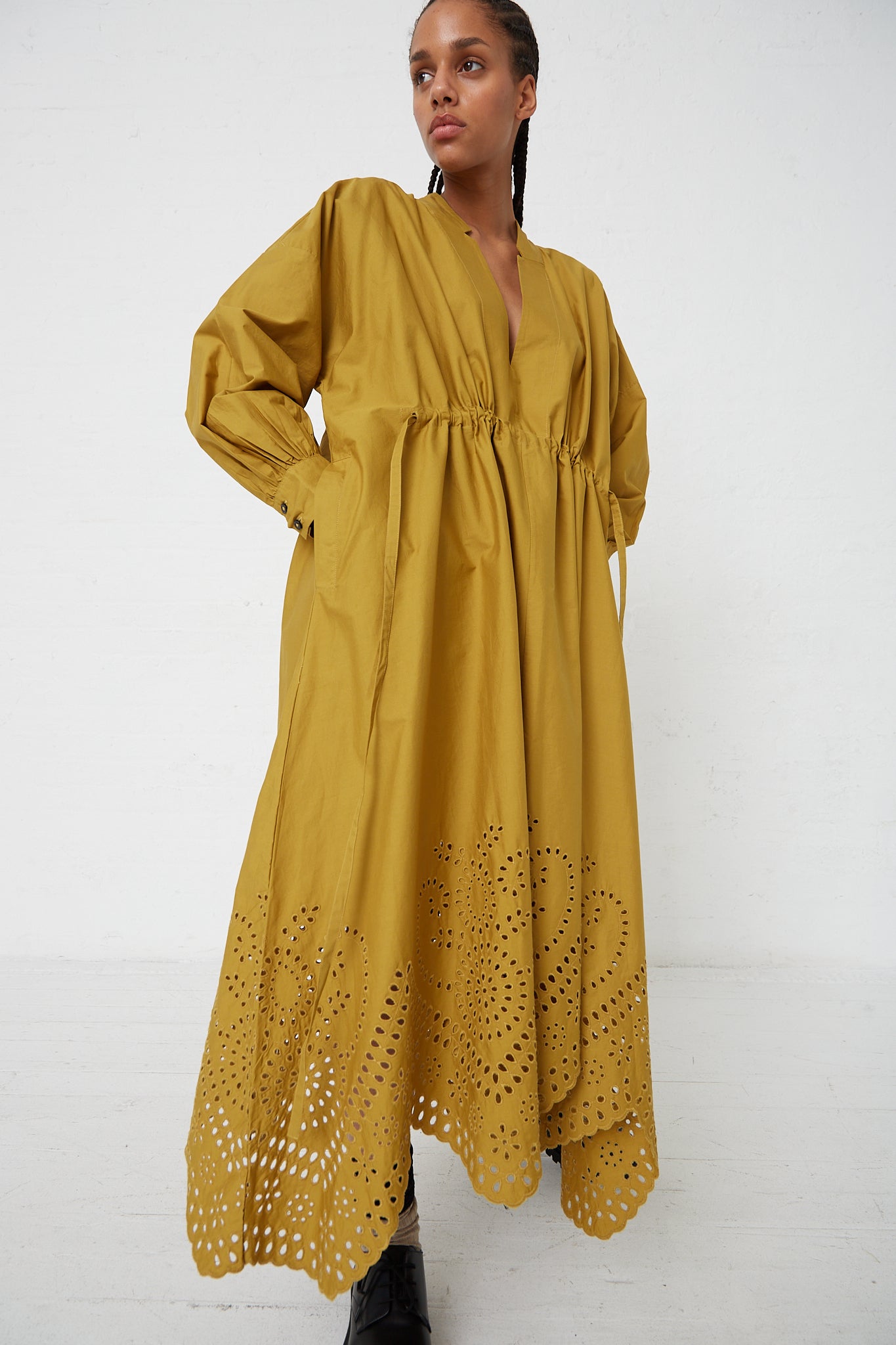 A woman wearing a Rachel Comey Bridge Dress with Hearts Eyelet in Chartreuse with a drawstring tie waist.
