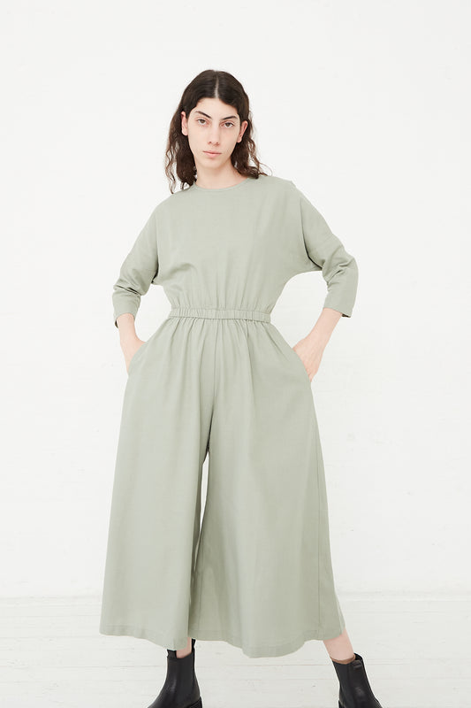 The model is wearing a Black Crane Cotton Twill Wide Culotte Jumpsuit in Agave green. Full length and front view.