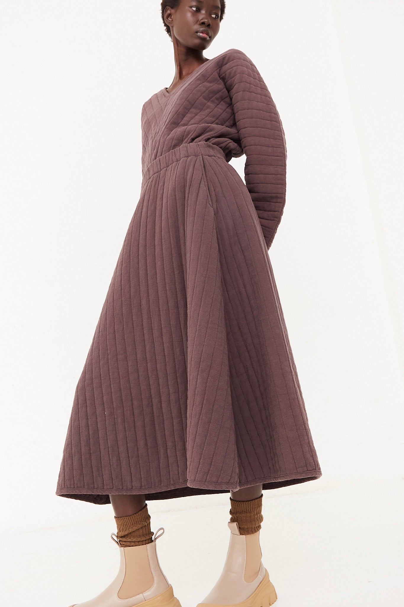 The model is wearing a brown quilted midi dress with an elasticated waist. 
Revised sentence: The model is wearing a plum quilted skirt with an elasticated waist by Black Crane.