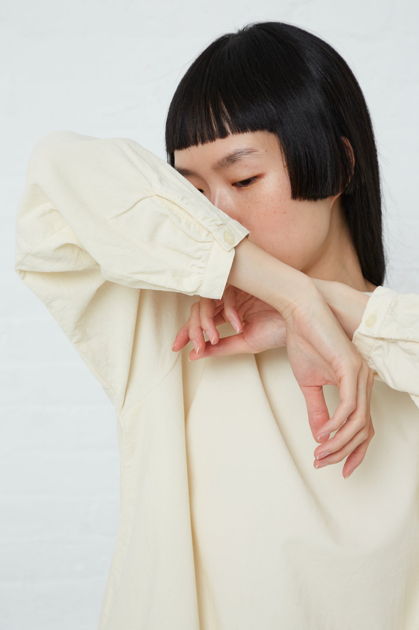 A woman wearing an Ichi cotton pullover top in Ivory with her hands on her face.