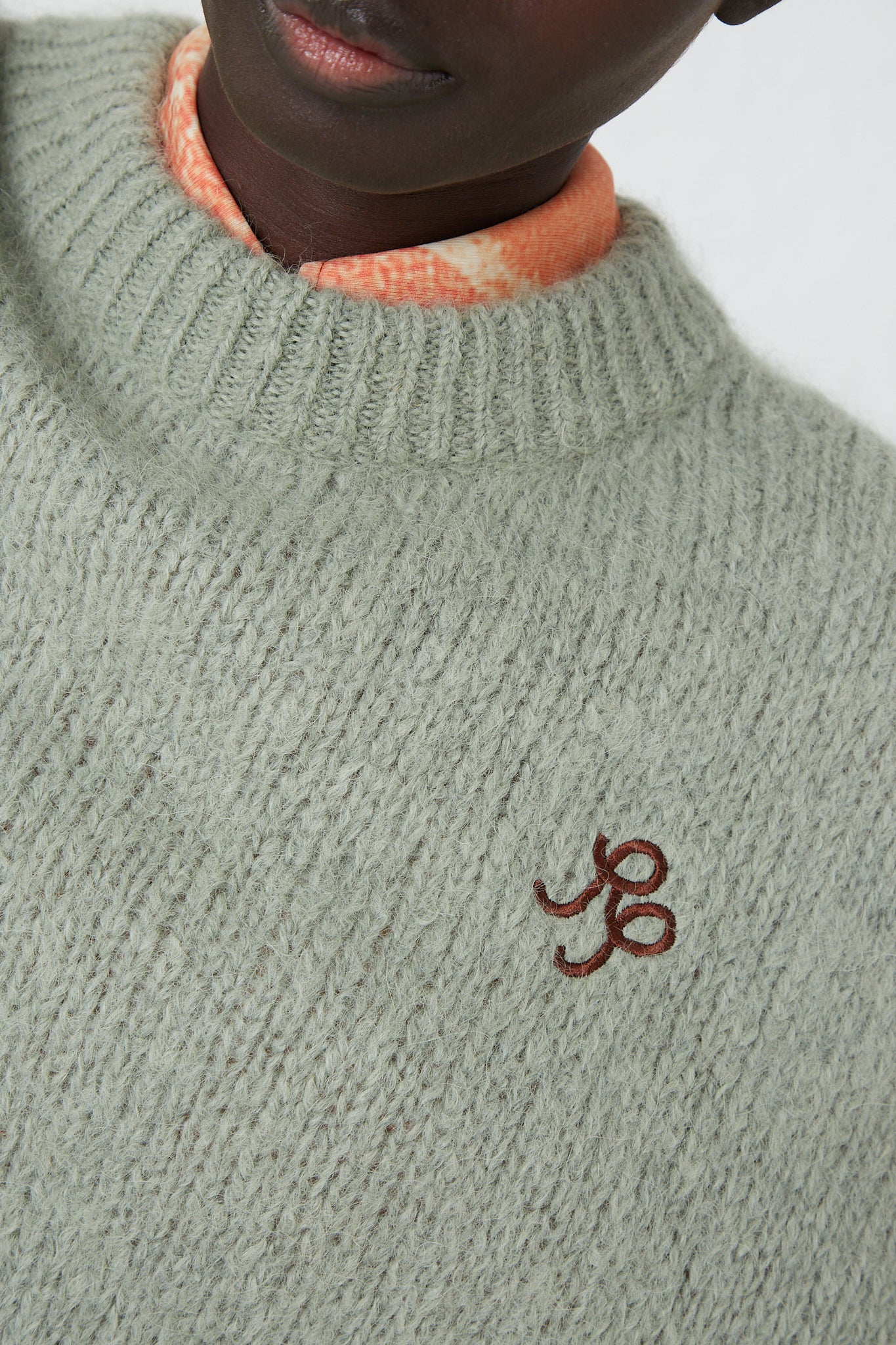 A woman wearing a green crew neck Alpaca Blend Toni Sweater in Mint with a brown Rejina Pyo logo detail.