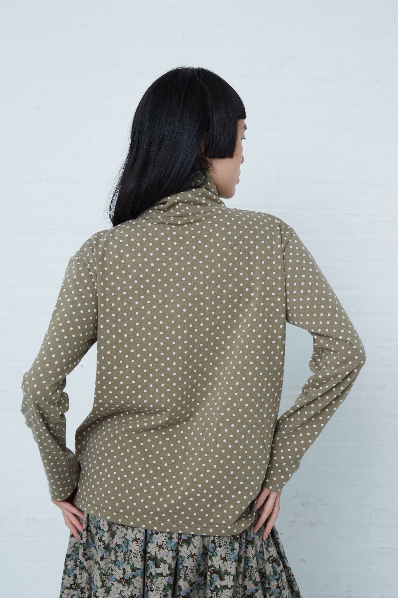 A woman wearing an Ichi Cotton Polka Dot Pullover Turtleneck in Khaki styled with a relaxed fit.