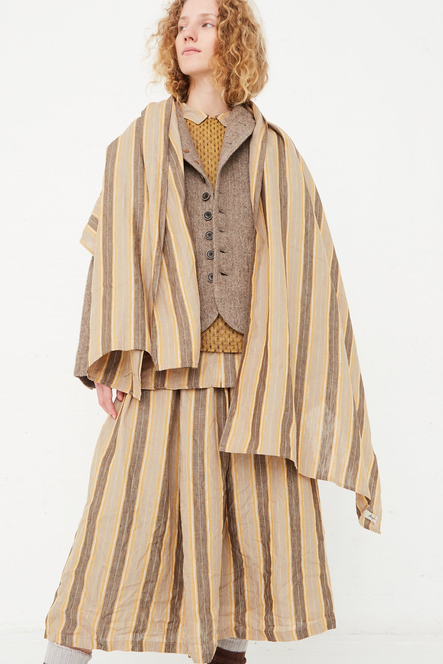 A model wearing an Ichi Antiquités Linen Stripe Stole in Mustard coat, available at Oroboro store in NYC.