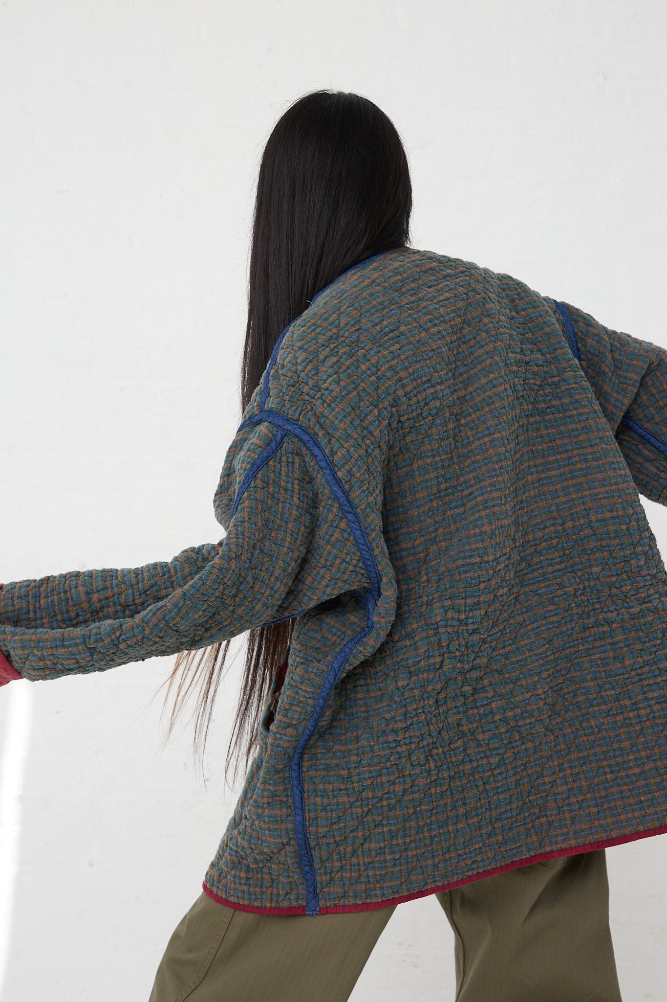 A woman wearing a As Ever Quilt Jacket in Mulberry. Reversed and back view.
