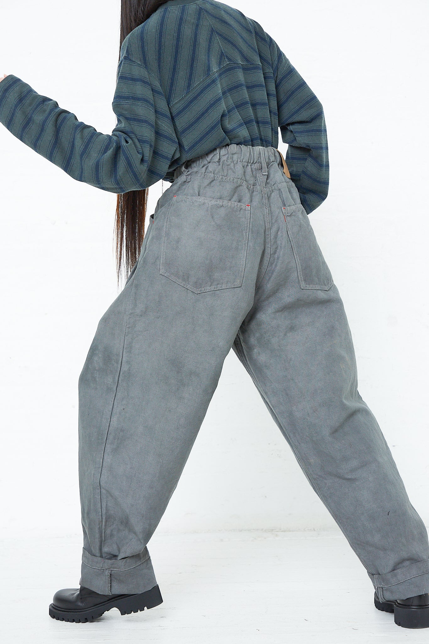 A woman wearing the Dr. Collectors 9 oz. Cotton and Hemp P40 Z Boys Military Pant in Swiss Army and a striped shirt. Back view.