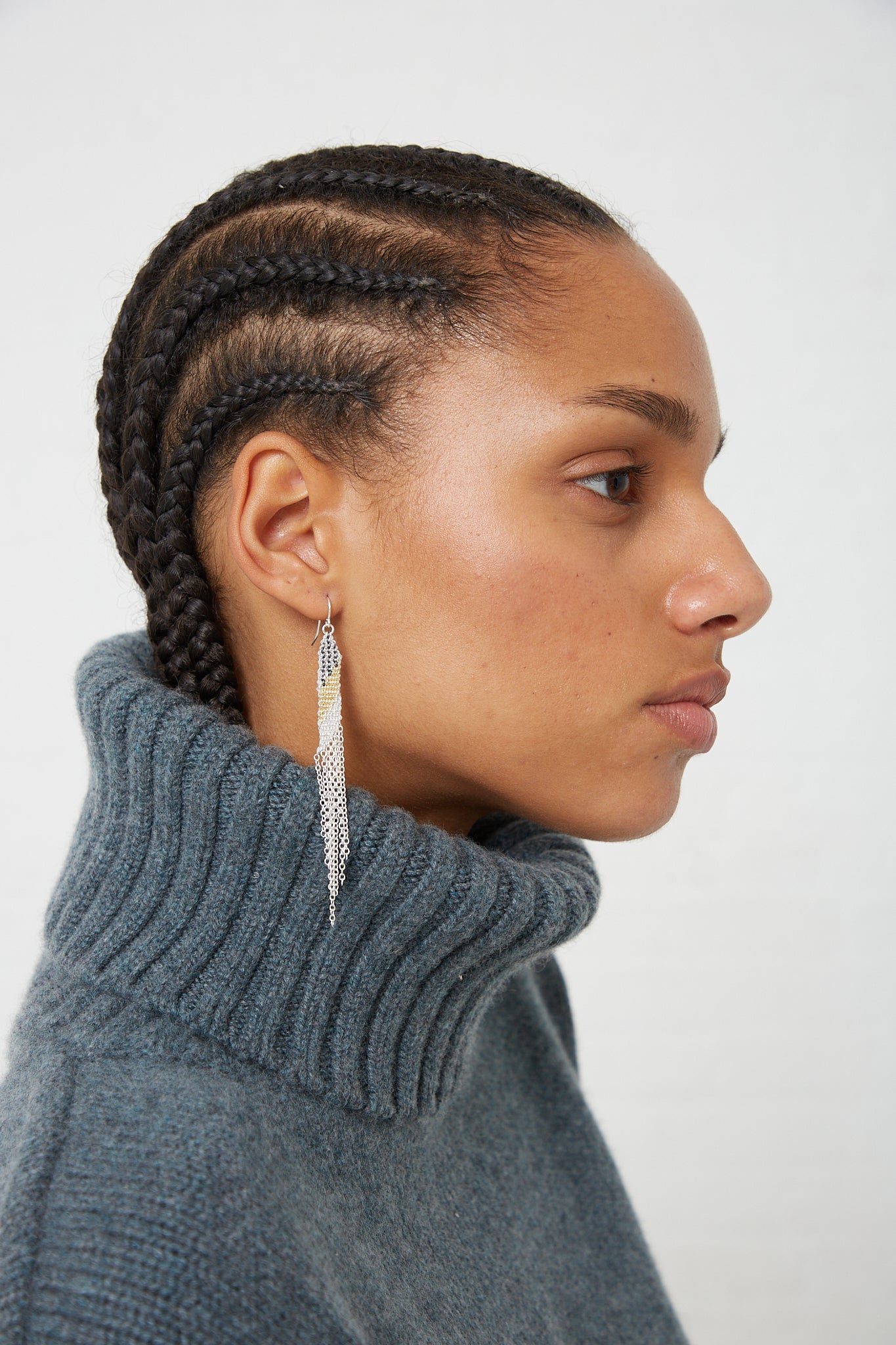 A woman wearing a turtle neck sweater and Stephanie Schneider's Sterling Silver Earrings in Silver Oxidized and Gold-Plated Silk.