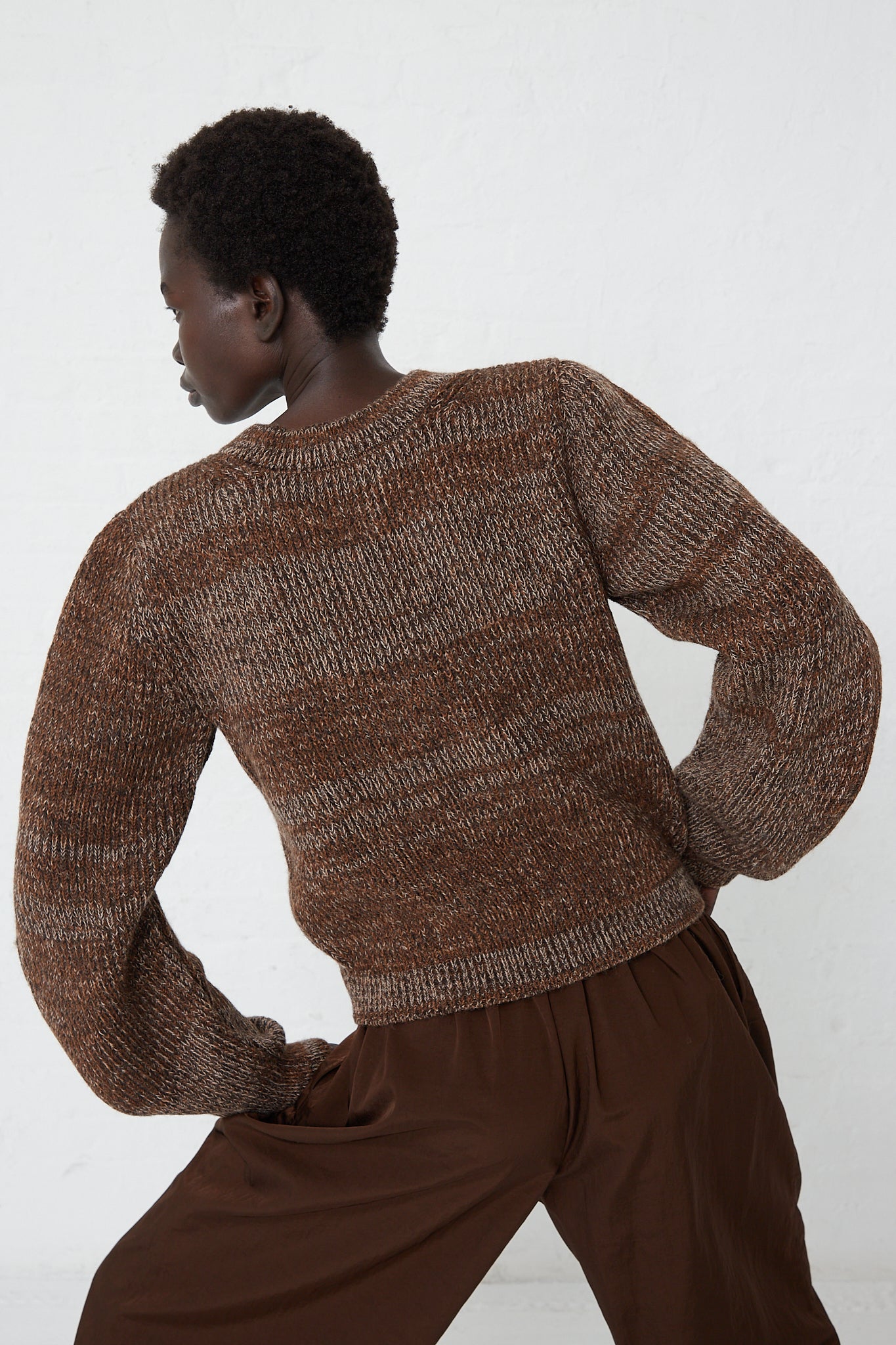 A woman wearing a Veronique Leroy Curved Sleeve Sweater in Oak made of virgin wool.