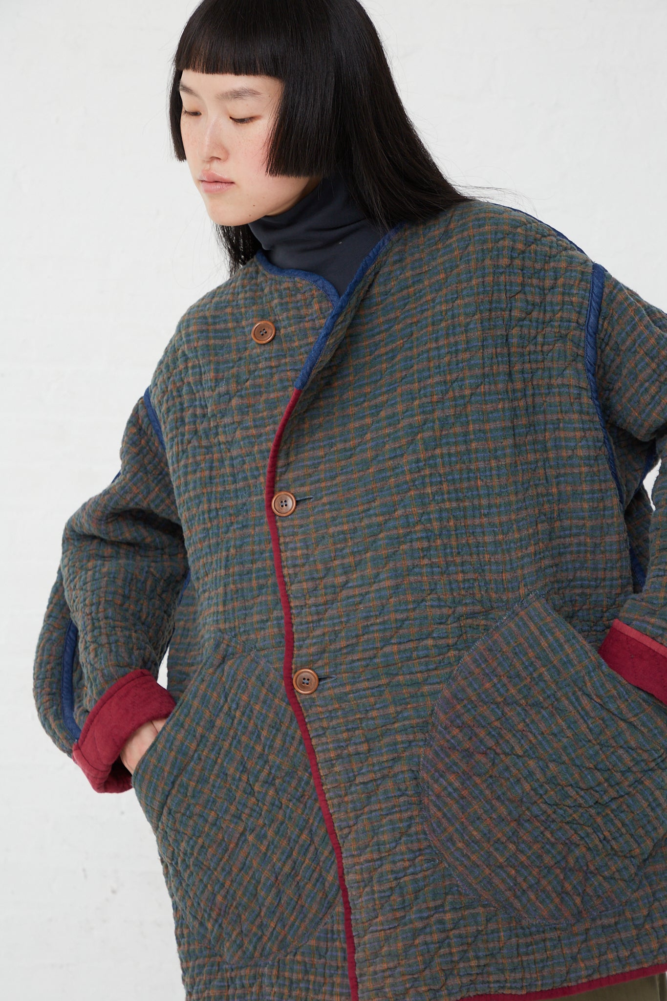 A woman wearing an As Ever oversized fit Quilt Jacket in Mulberry with a turtle neck. Reversed.