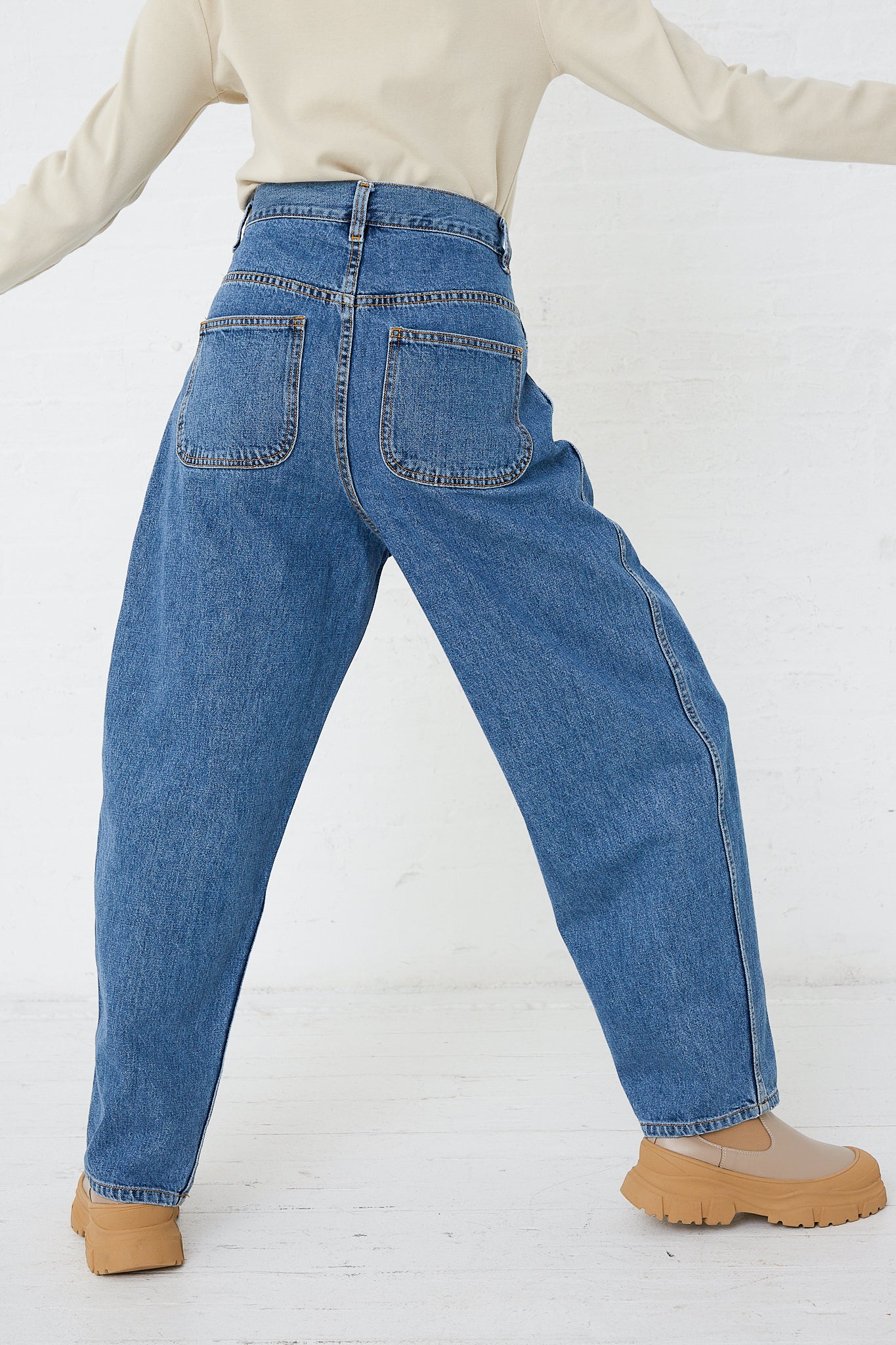 A woman wearing a pair of high waisted Jesse Kamm Japanese Denim California Wide jeans in Cowboy Blue and a tee shirt.