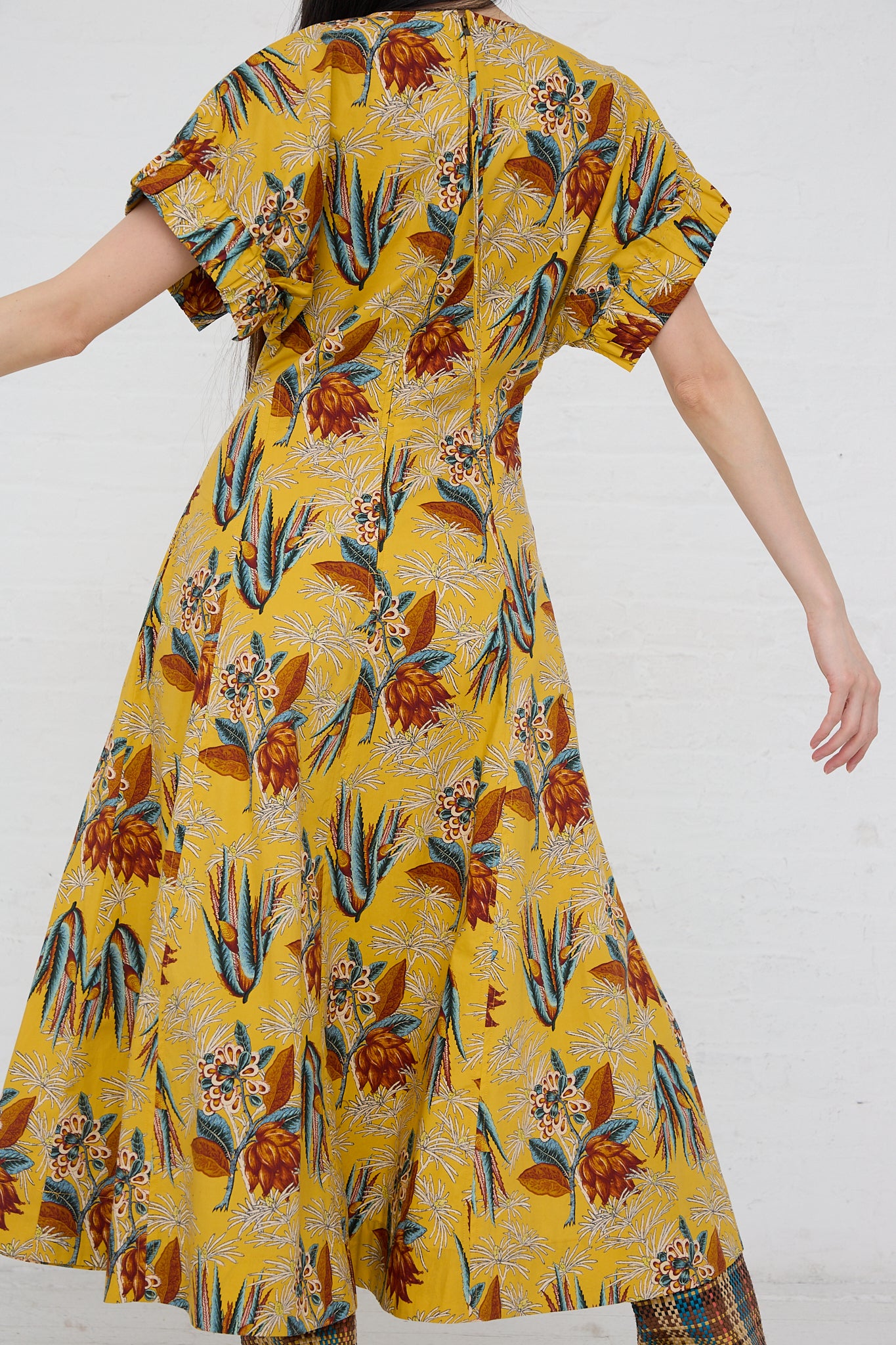 A woman wearing a Devon Dress in Marigold from Ulla Johnson, featuring a tapestry print.