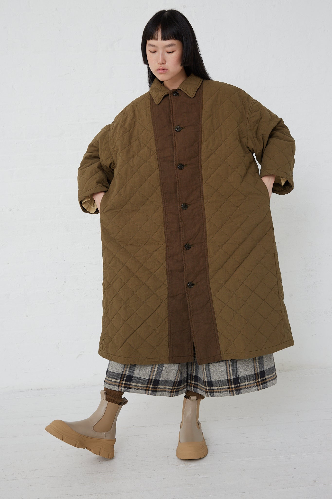 A woman wearing an oversized, nest Robe Cotton Ramie Quilted Long Coat in Olive.