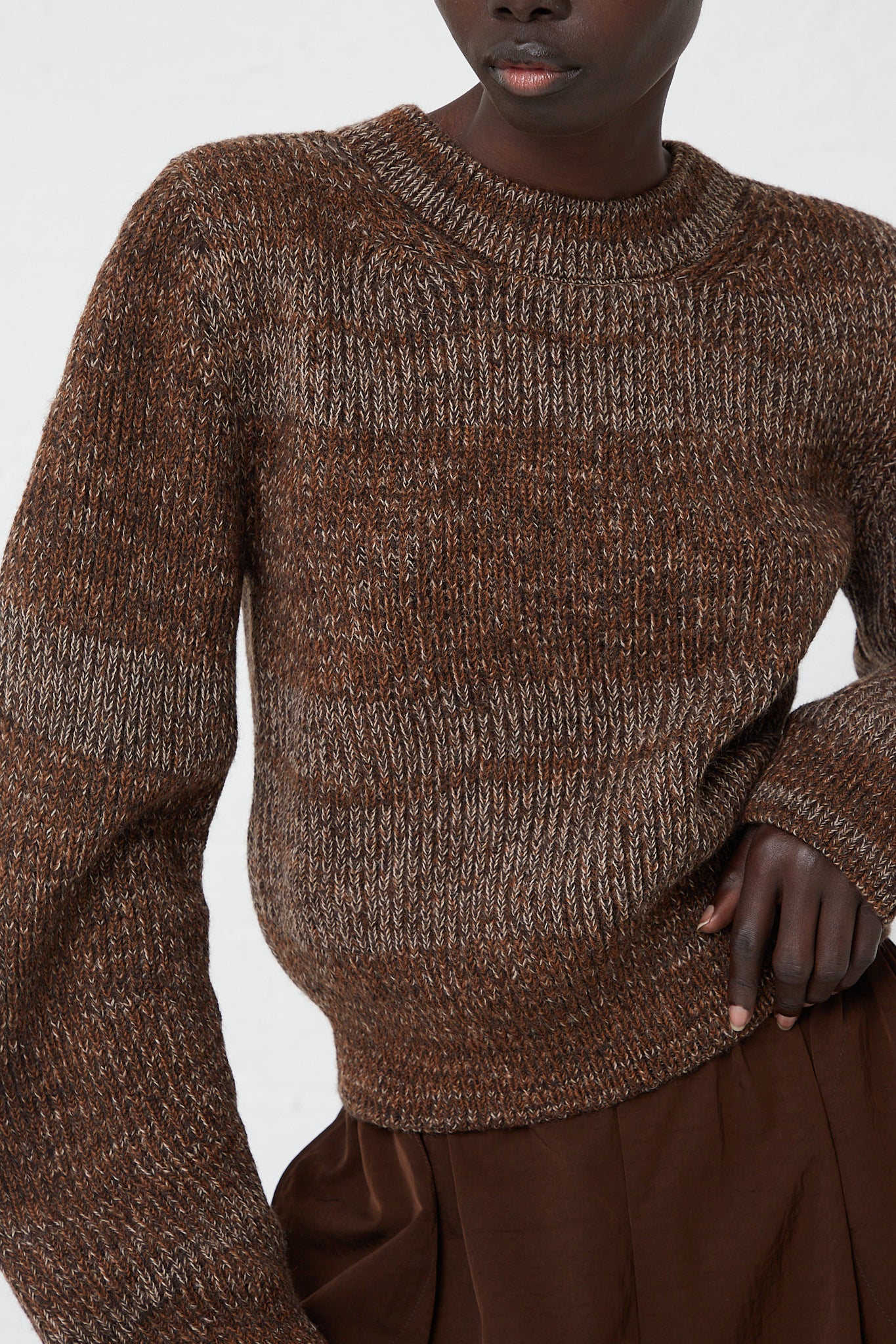 A woman wearing a Veronique Leroy Curved Sleeve Sweater in Oak, a relaxed fit, made of virgin wool.