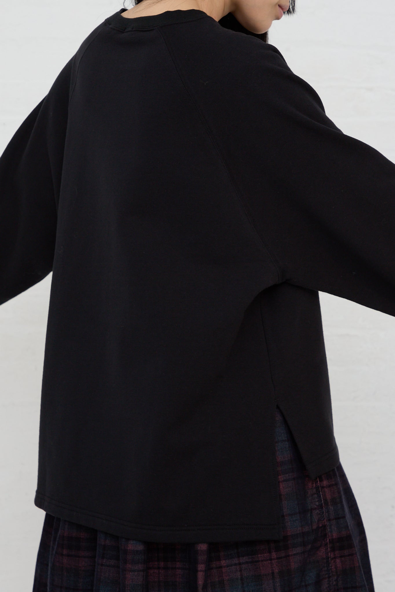 The back of a woman wearing an Ichi black relaxed fit long sleeve Cotton Knit Pullover and plaid skirt.
