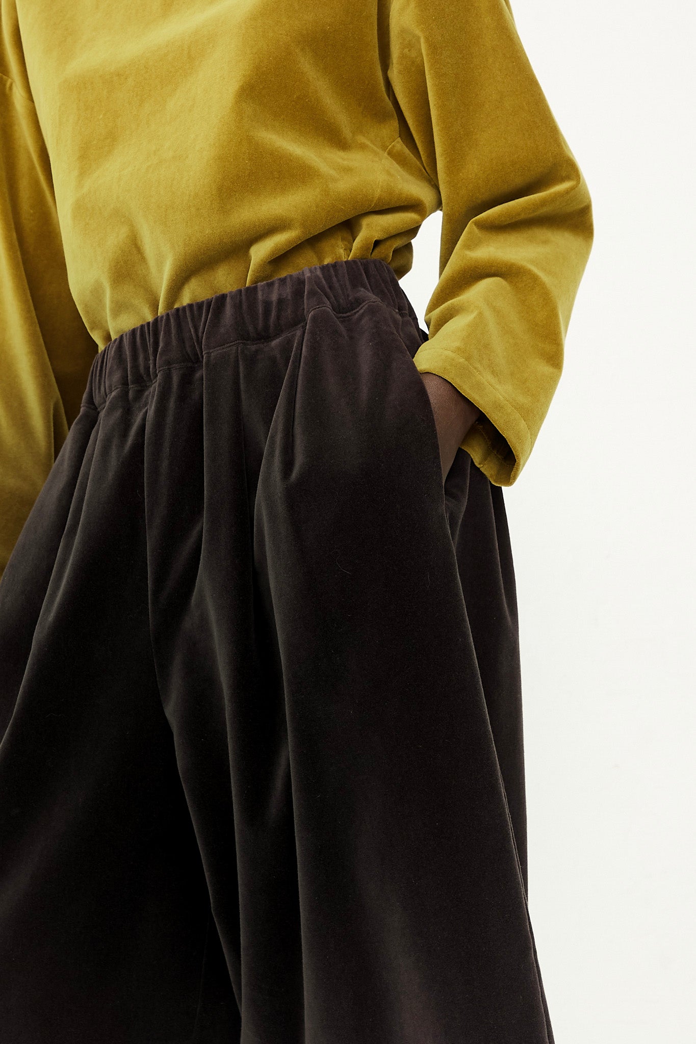 A woman wearing a yellow shirt and Cotton Velveteen Wide Pants in Sumi Black by Black Crane with an elasticated waist.