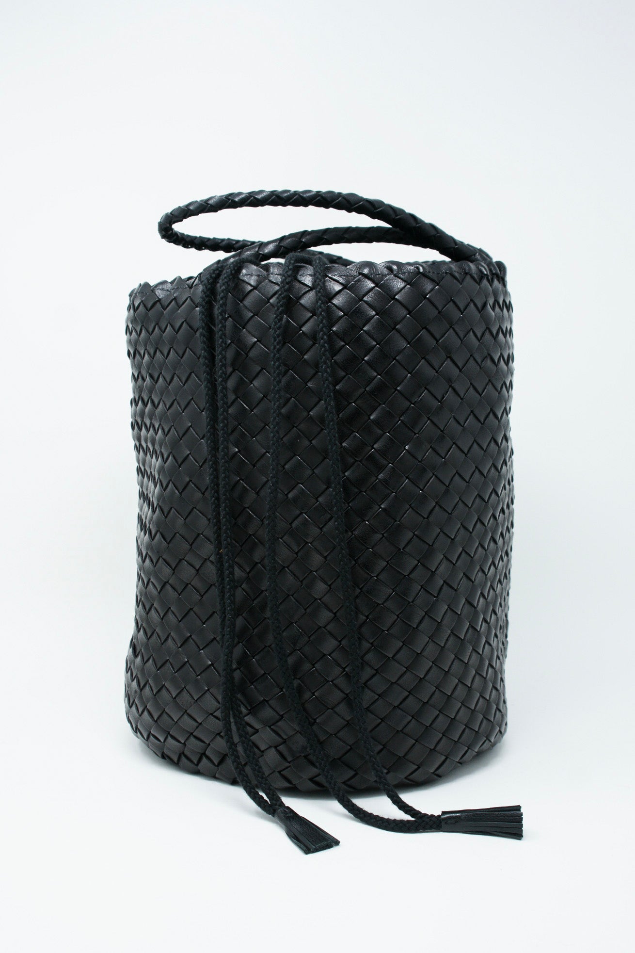 A Jacky Bucket Bag in Black, crafted using handwoven techniques and showcased on a pristine white background, made by Dragon Diffusion.
