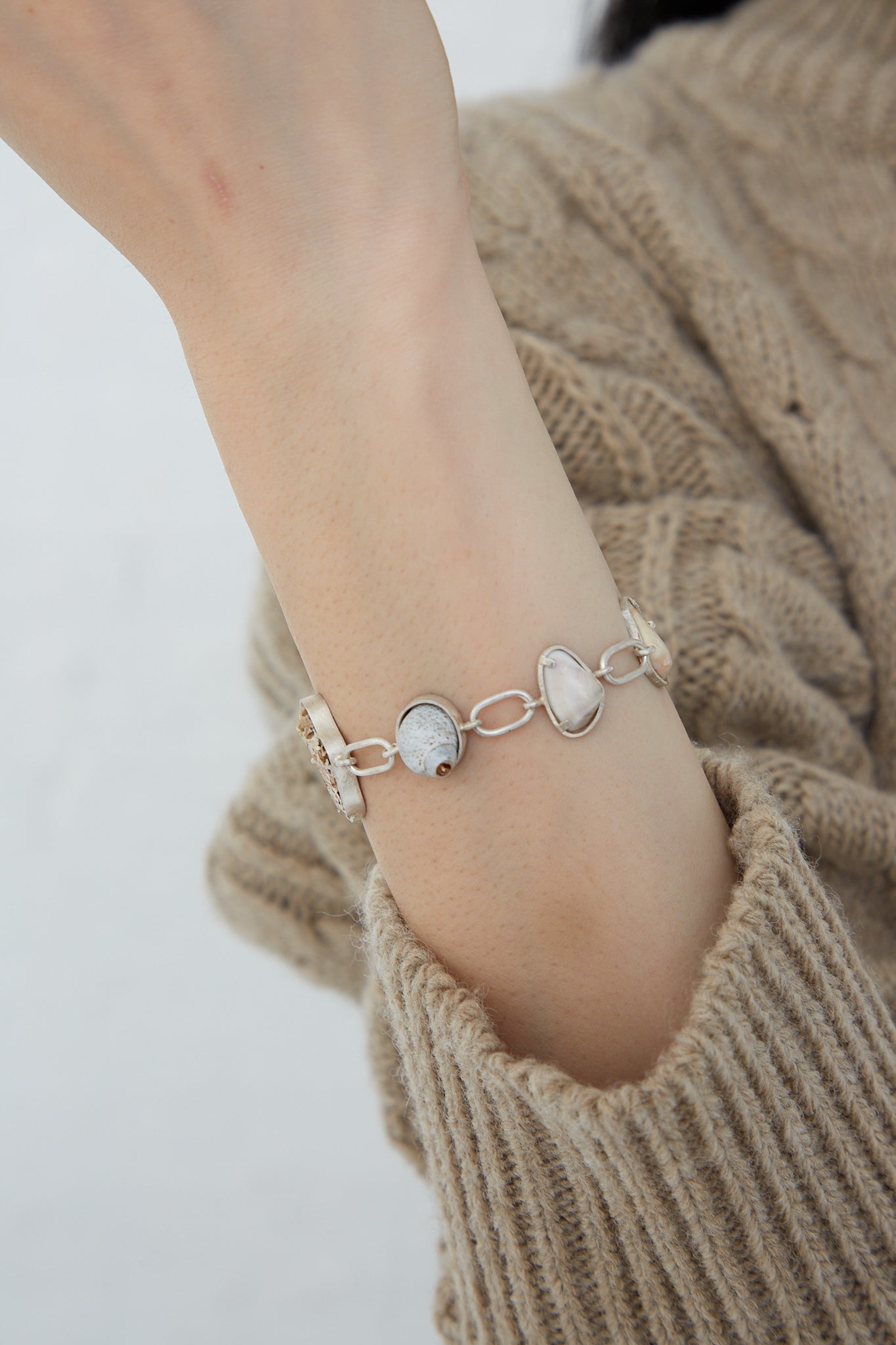A woman wearing a one-of-a-kind La Mar Sterling Silver Bracelet 001 A with pearls and found shells.
