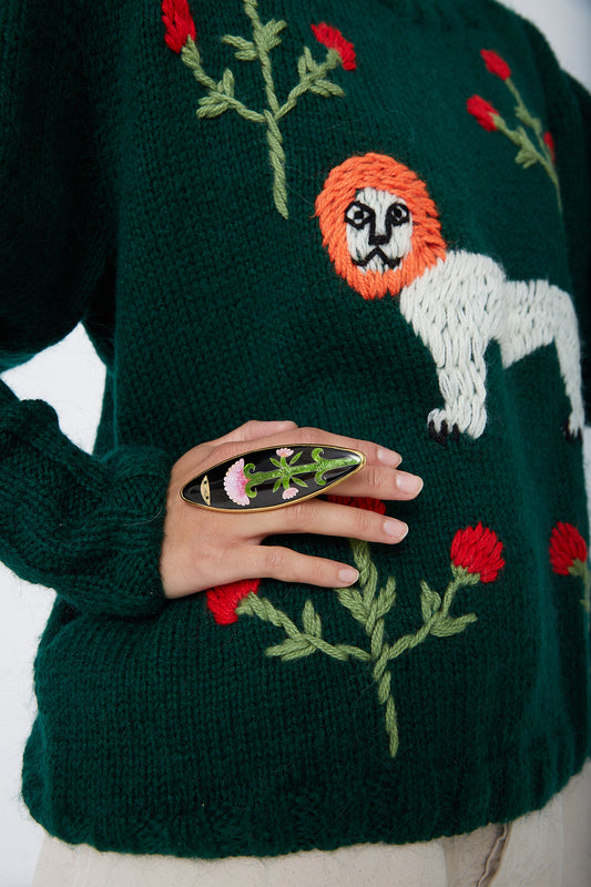 A woman wearing a green sweater and a black Sofio Gongli Pink Floral with Eyes enamel ring.