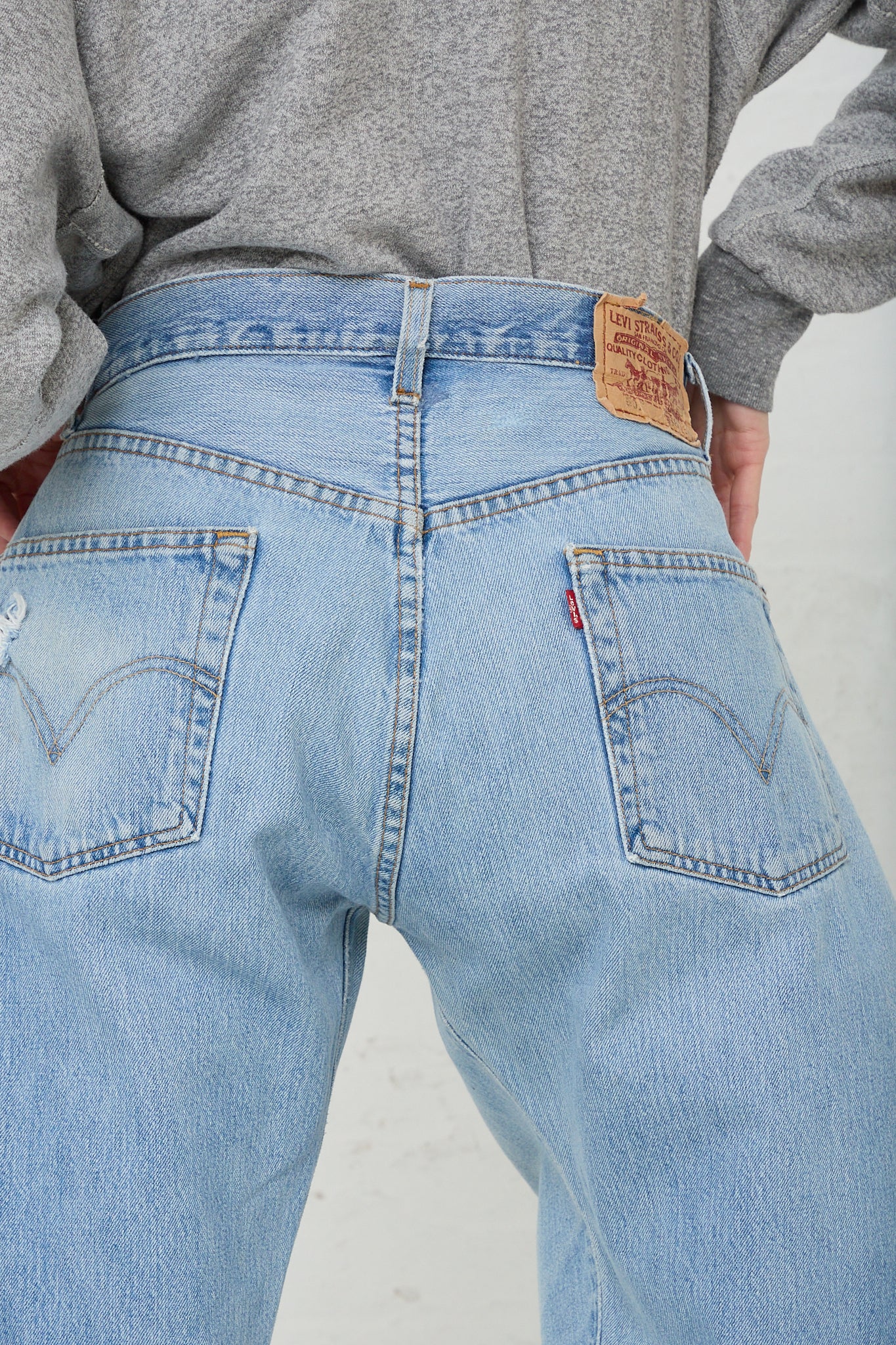 The back of a woman wearing a pair of B Sides Lasso Jean in Vintage Indigo with a cutoff frayed hem. Up close view highlighting back pocket details.