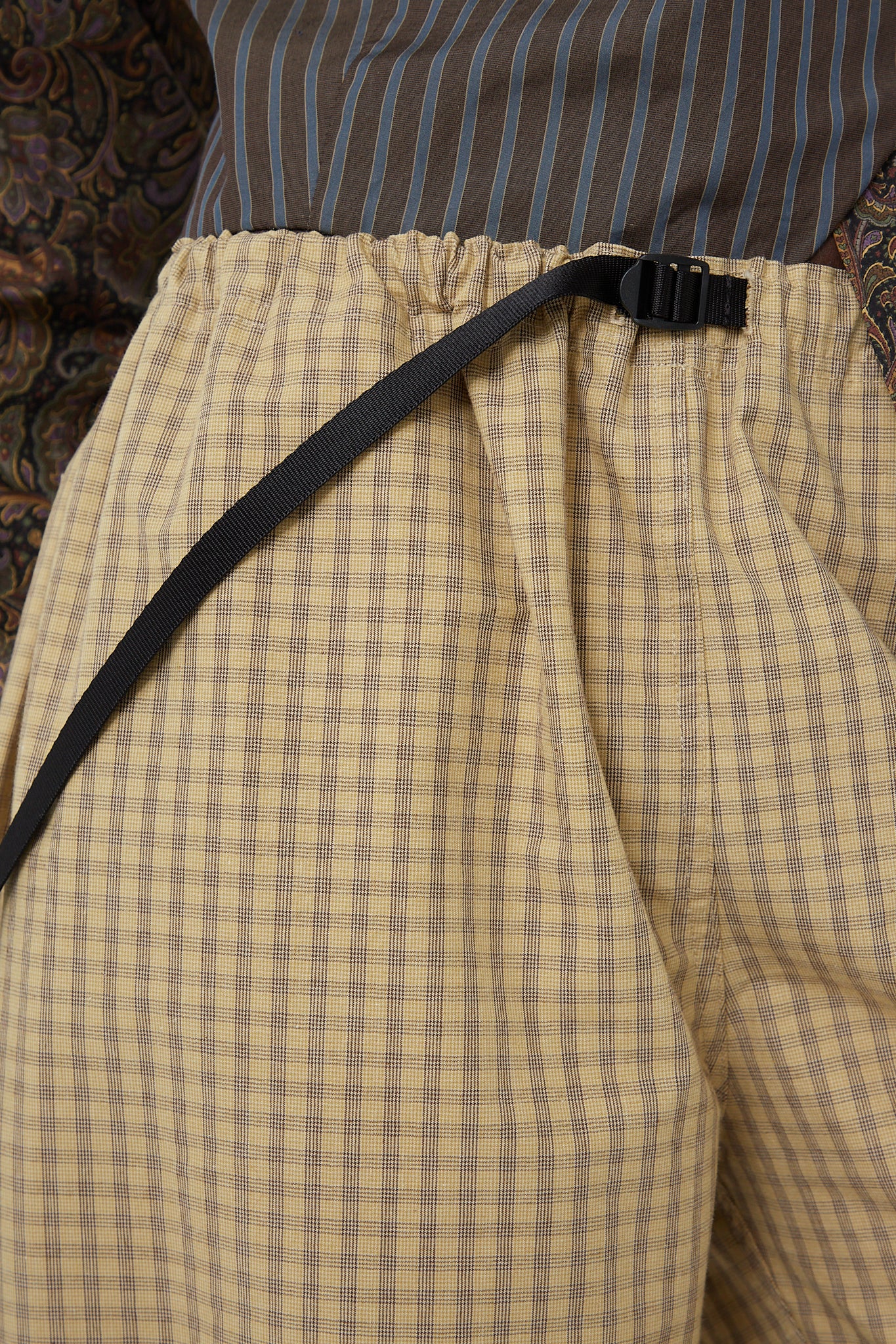 An up-close view of a model in a plaid shirt and SC103 pants with an adjustable waist belt around his waist.