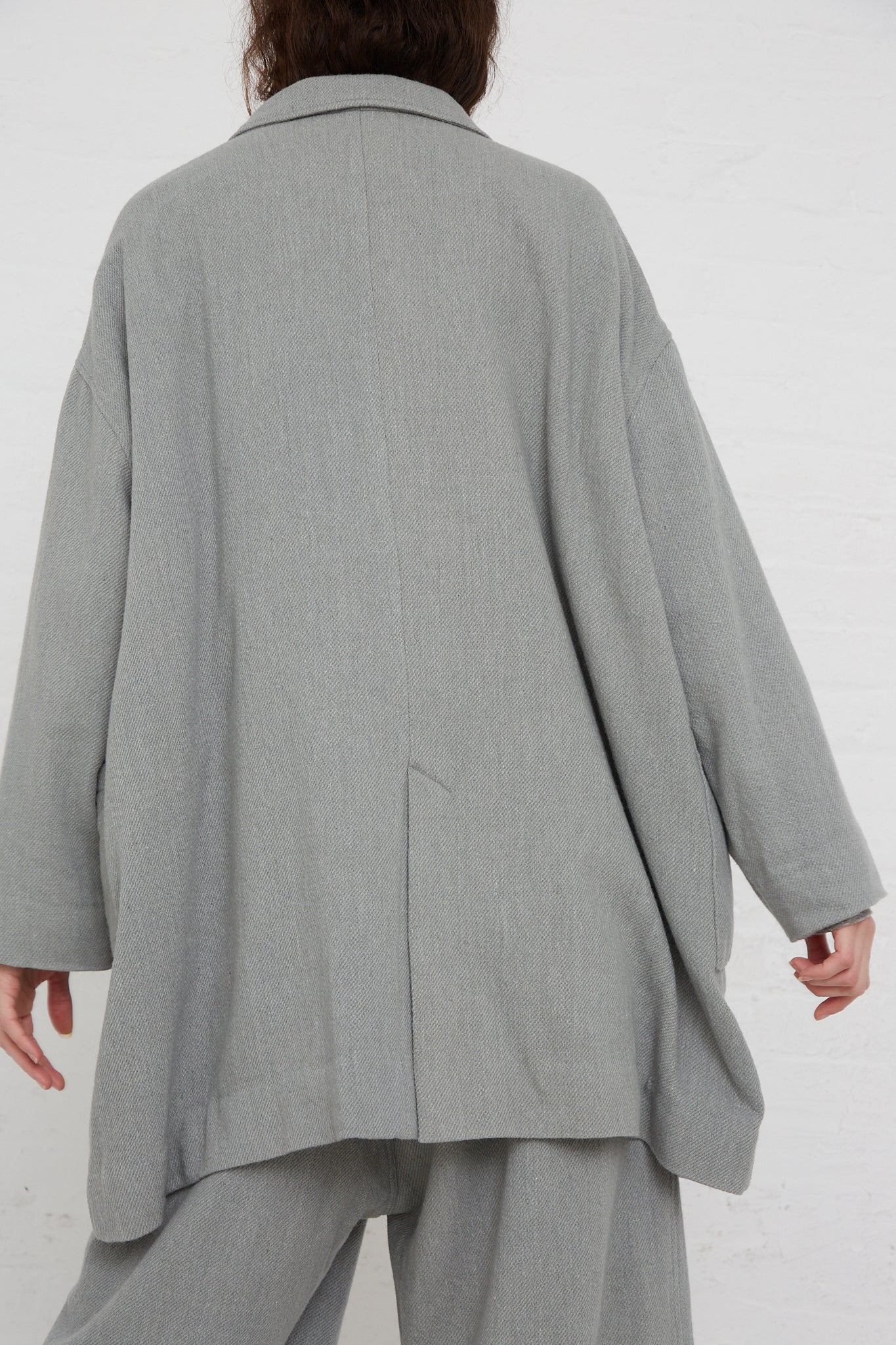 The woman wearing an oversized Ichi Antiquités Merino Wool Orihimedaki Jacket in Blue with patch pockets. Back view.