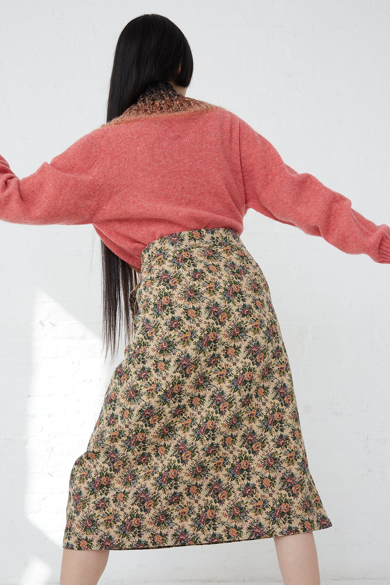 A woman in a pink sweater and SMLXL Skirt No. 75 in Flower from the Bless luxury lifestyle brand.