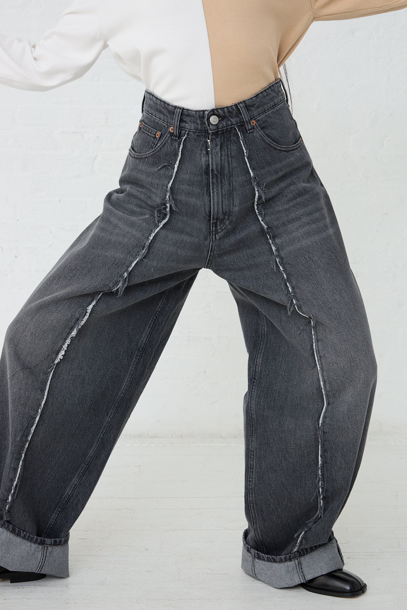 A woman is wearing a pair of MM6 5 Pockets Pant in Grey denim. Front view and full length. Model is leaning slightly and arms are raised..