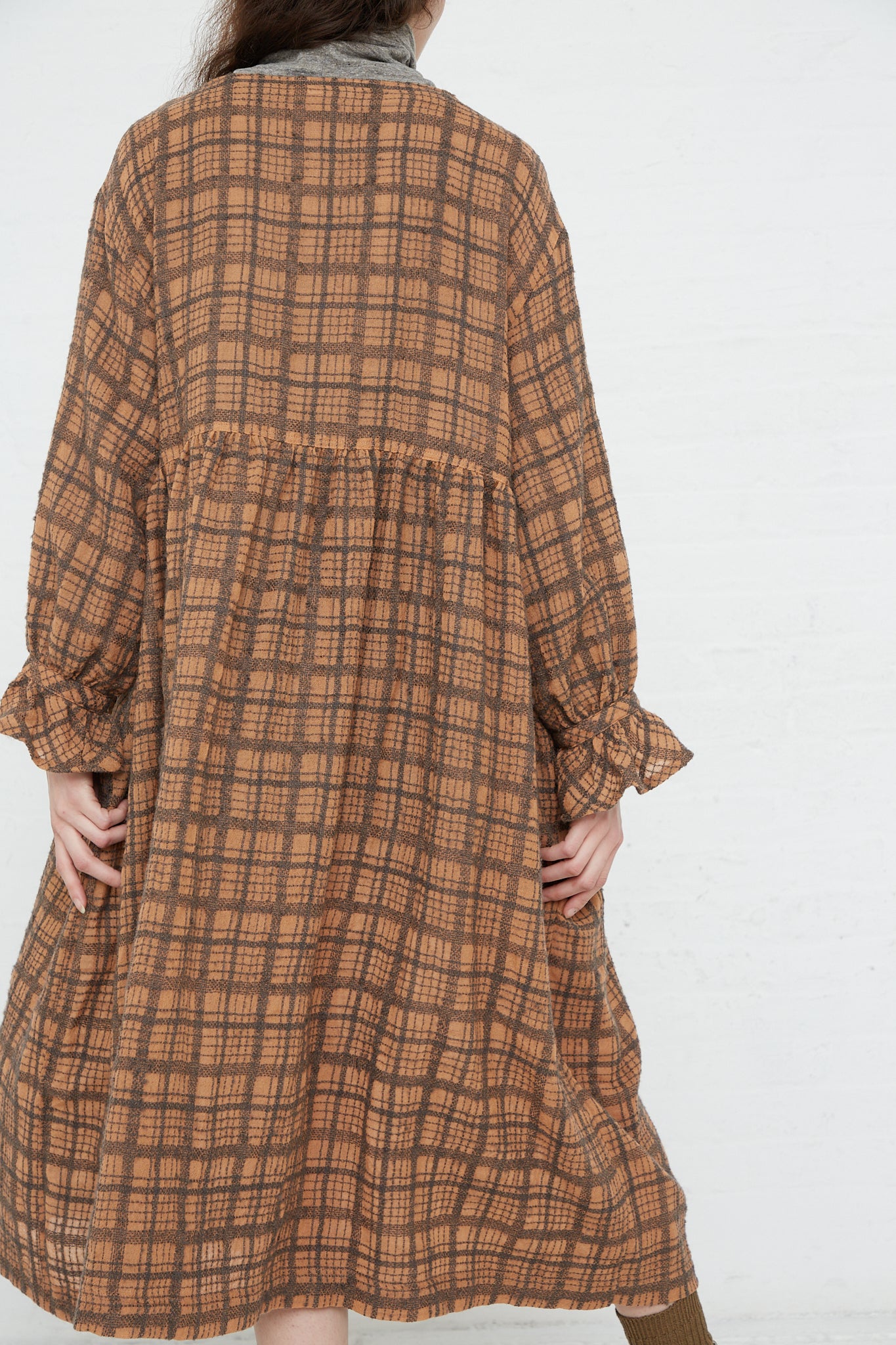 The woman is seen from the back, showcasing her beautiful and stylish Woven Wool Check Dress in Terracotta by Ichi Antiquités.