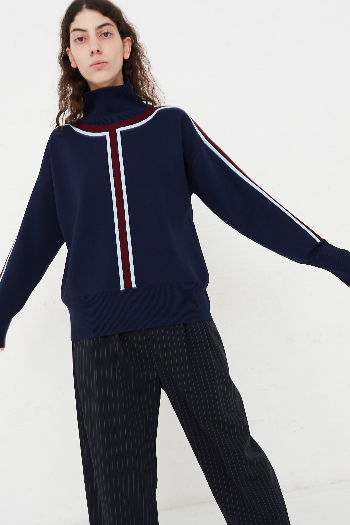 A model is wearing a Nomia brand Track Stripe Mockneck Sweater in Midnight at Oroboro Store.