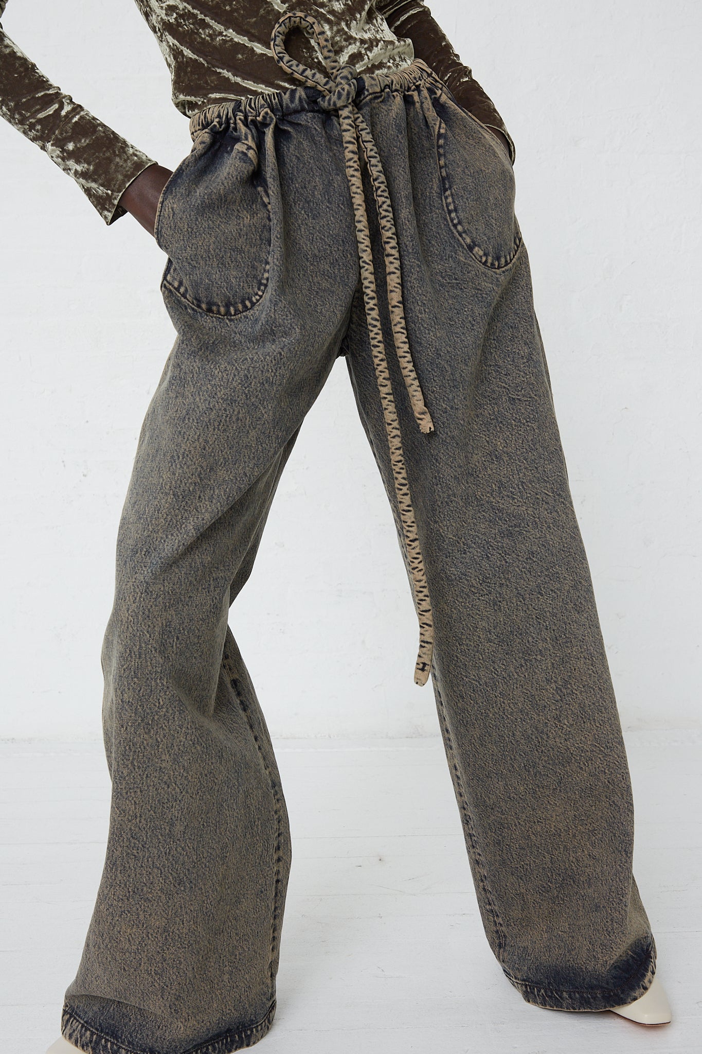 A woman wearing Veronique Leroy Denim Belted Trousers in Acid Wash Denim, featuring an adjustable drawstring waist.