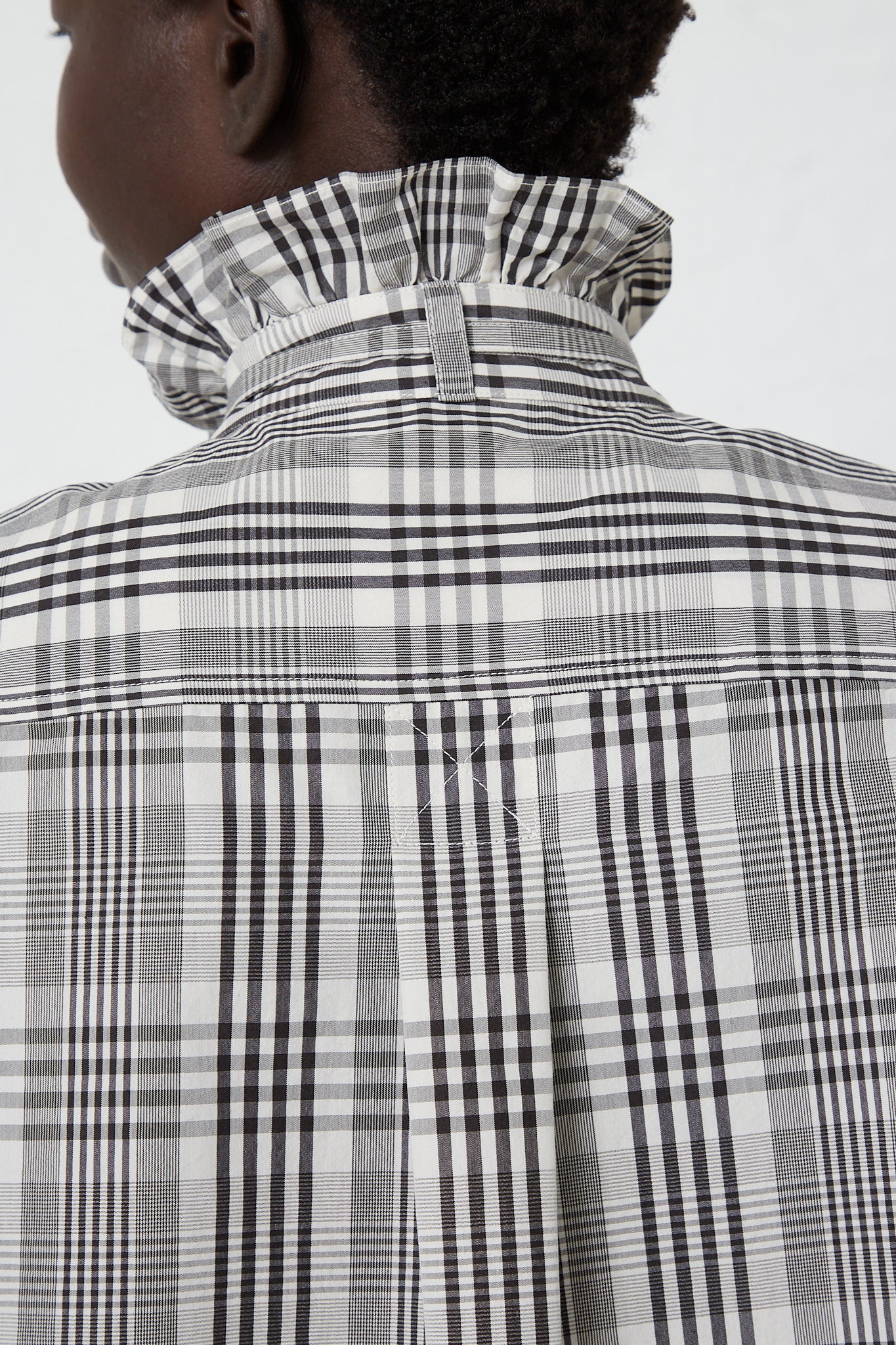 The back of a woman wearing a KasMaria Poplin Tie Shirt with Ruffle Collar in Heavy Plaid. Up close back view of collar.