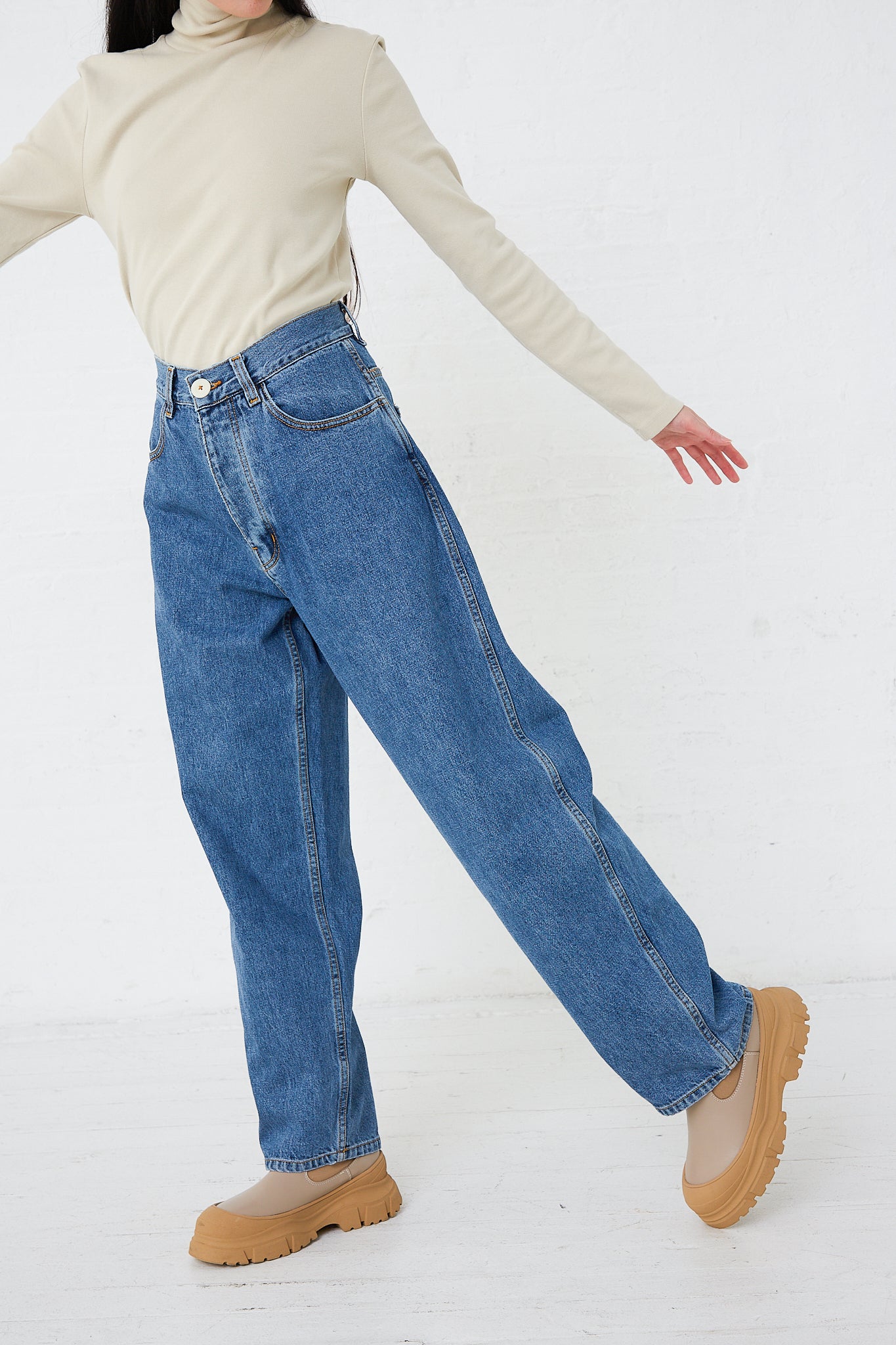 A woman wearing Jesse Kamm's Japanese Denim California Wide in Cowboy Blue pants, complemented by a minimalist turtleneck.