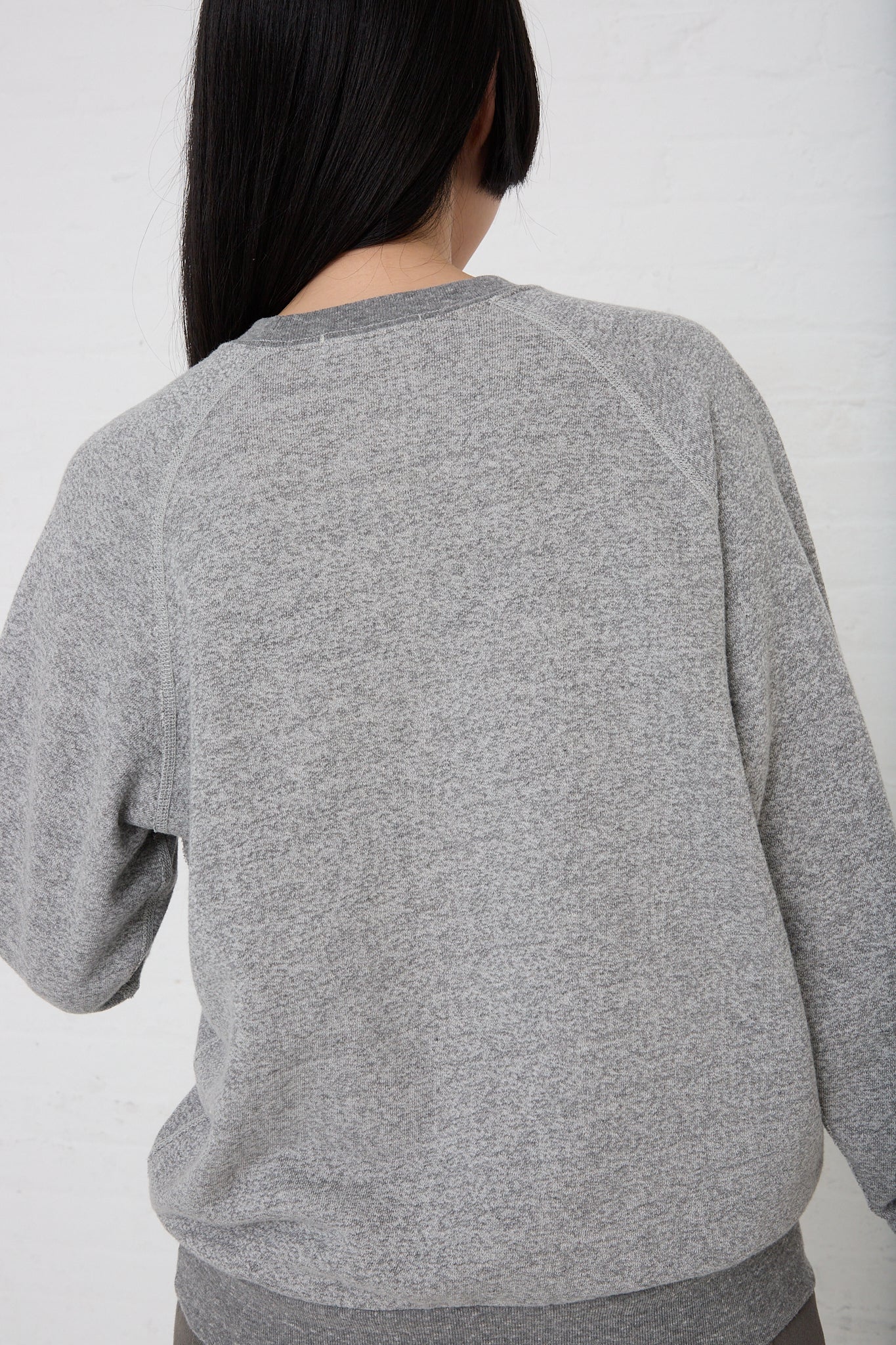 A woman wearing a B Sides French Terry Sweatshirt in Heather Grey. Back view.