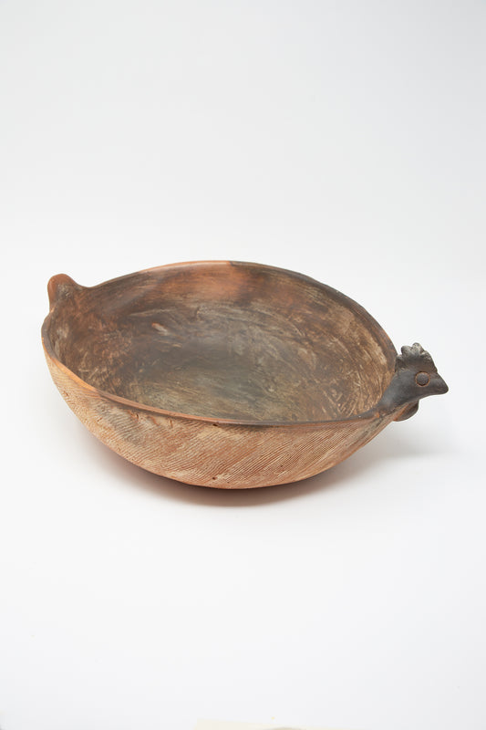 A Plaza Bolivar rustic Julia Bowl of Illusions in Red Clay with a wooden handle on a white surface.
