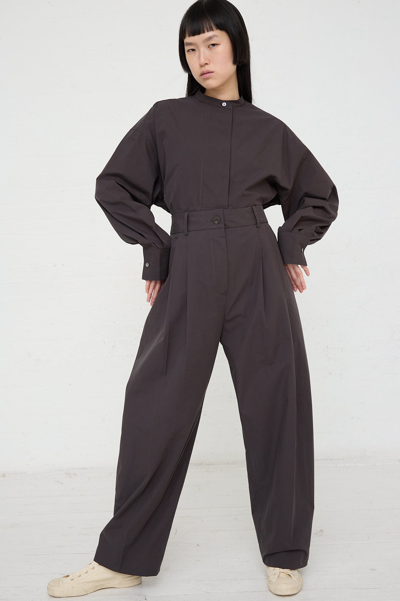 The model is wearing an Acuna Double Pleat Front Trouser in Asphalt by Studio Nicholson. Front view and full length.
