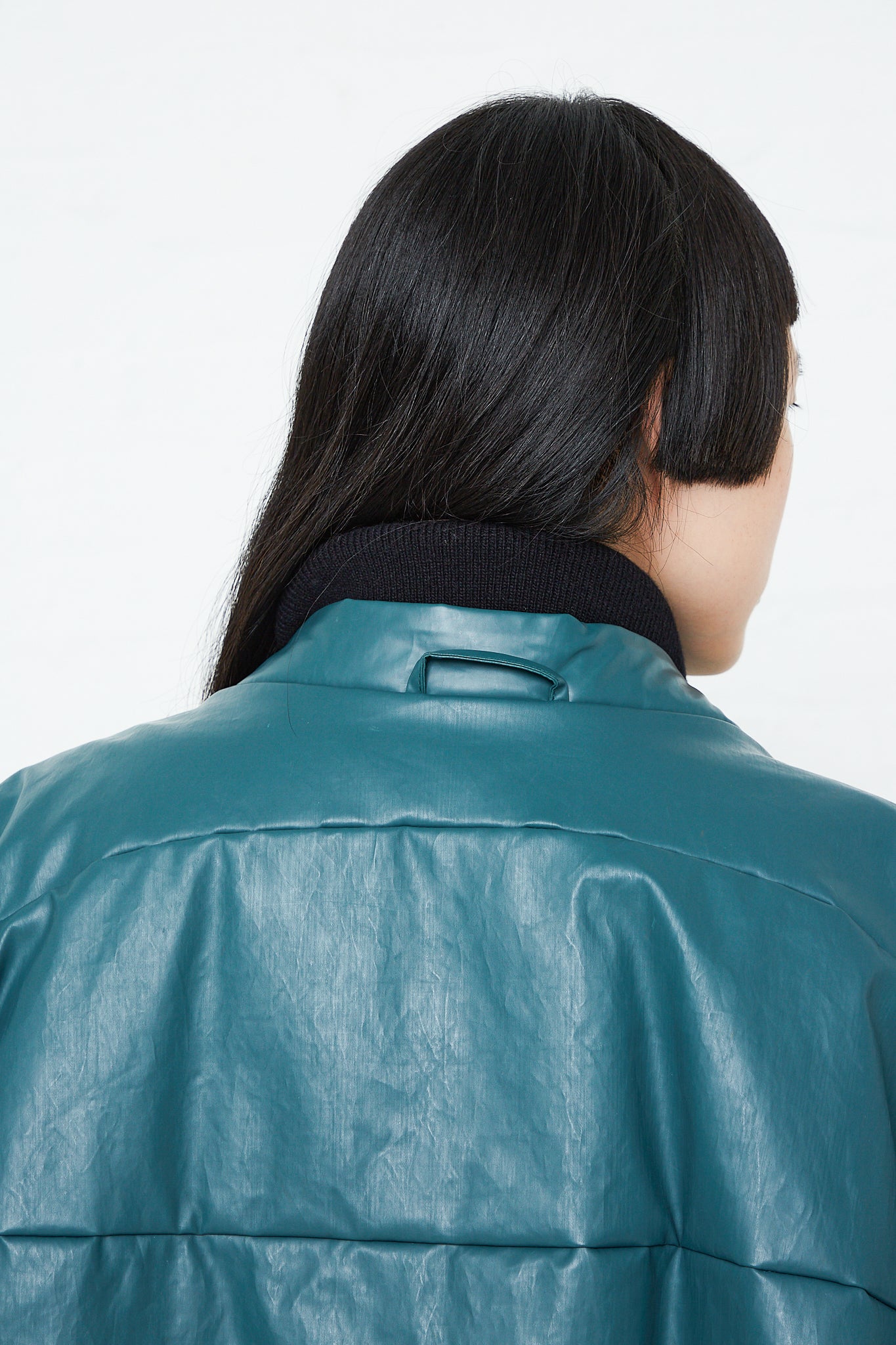 The back view of a woman wearing an Oversized Padded Bomber Oil Jacket in Forest made by Kassl.