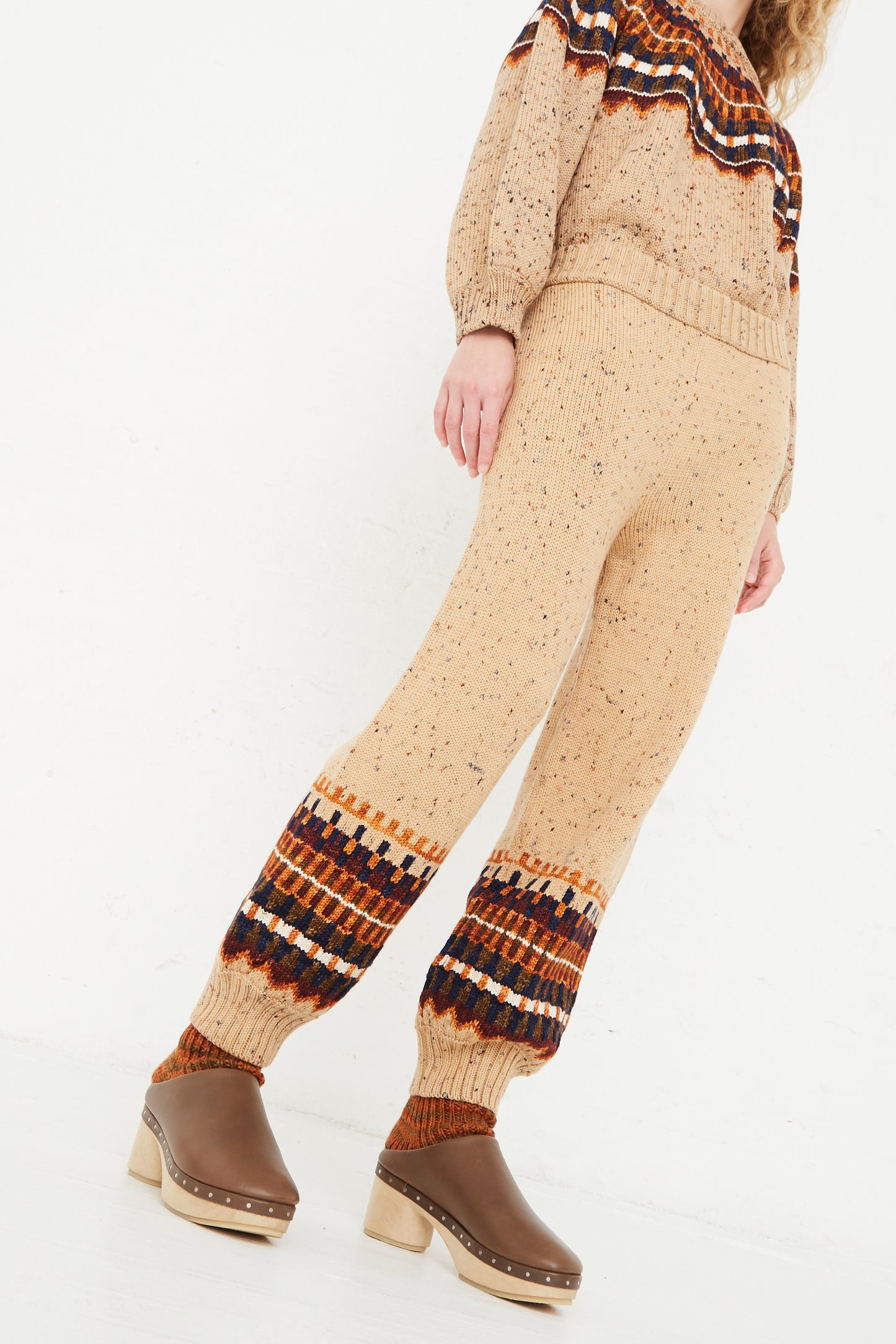 A model wearing a beige sweater and brown boots with the Fair Isle Warm-Up Pant in Seed Confetti from Misha & Puff.