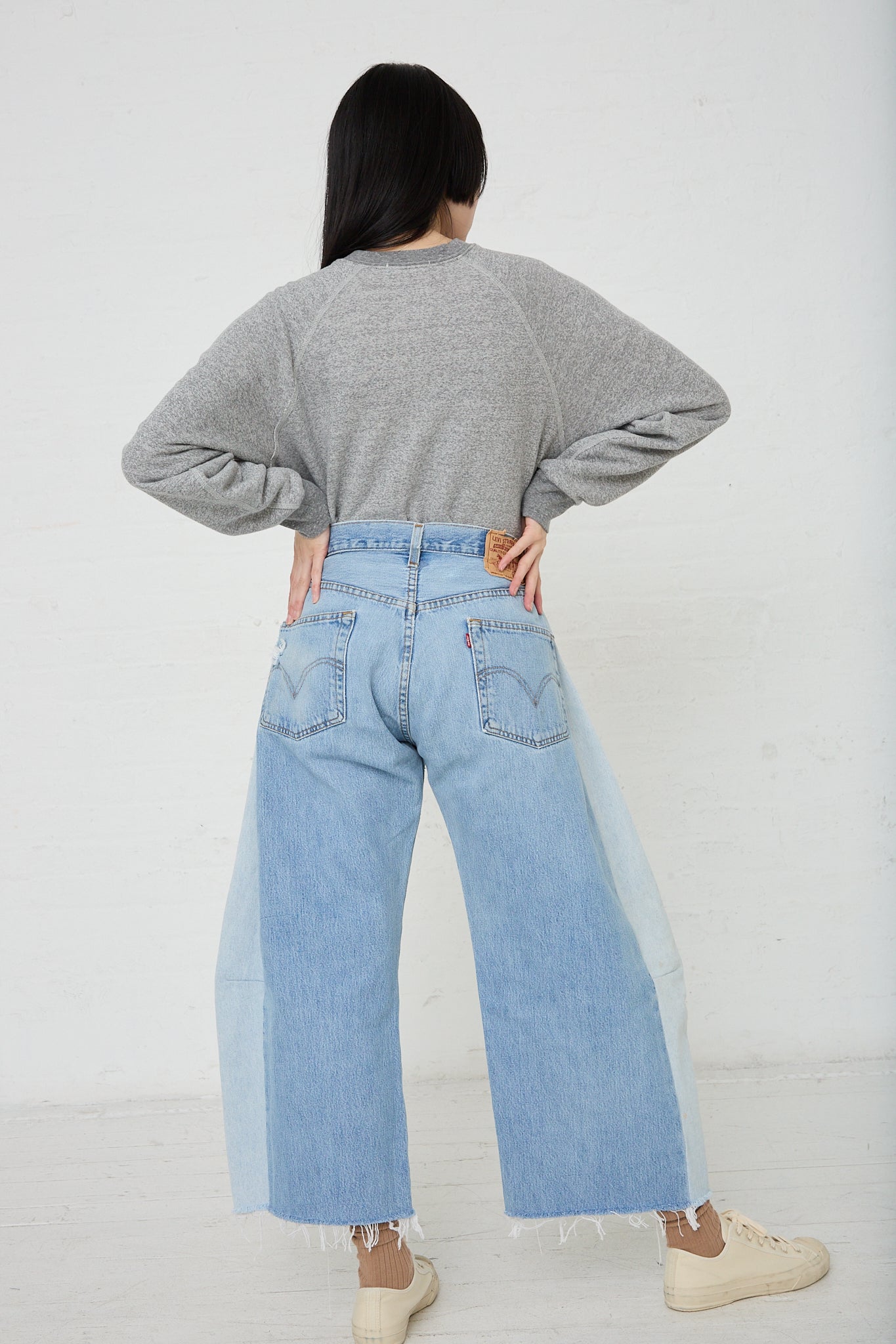 A woman in B Sides' Lasso Jean in Vintage Indigo with a cutoff frayed hem. Back view and full length.