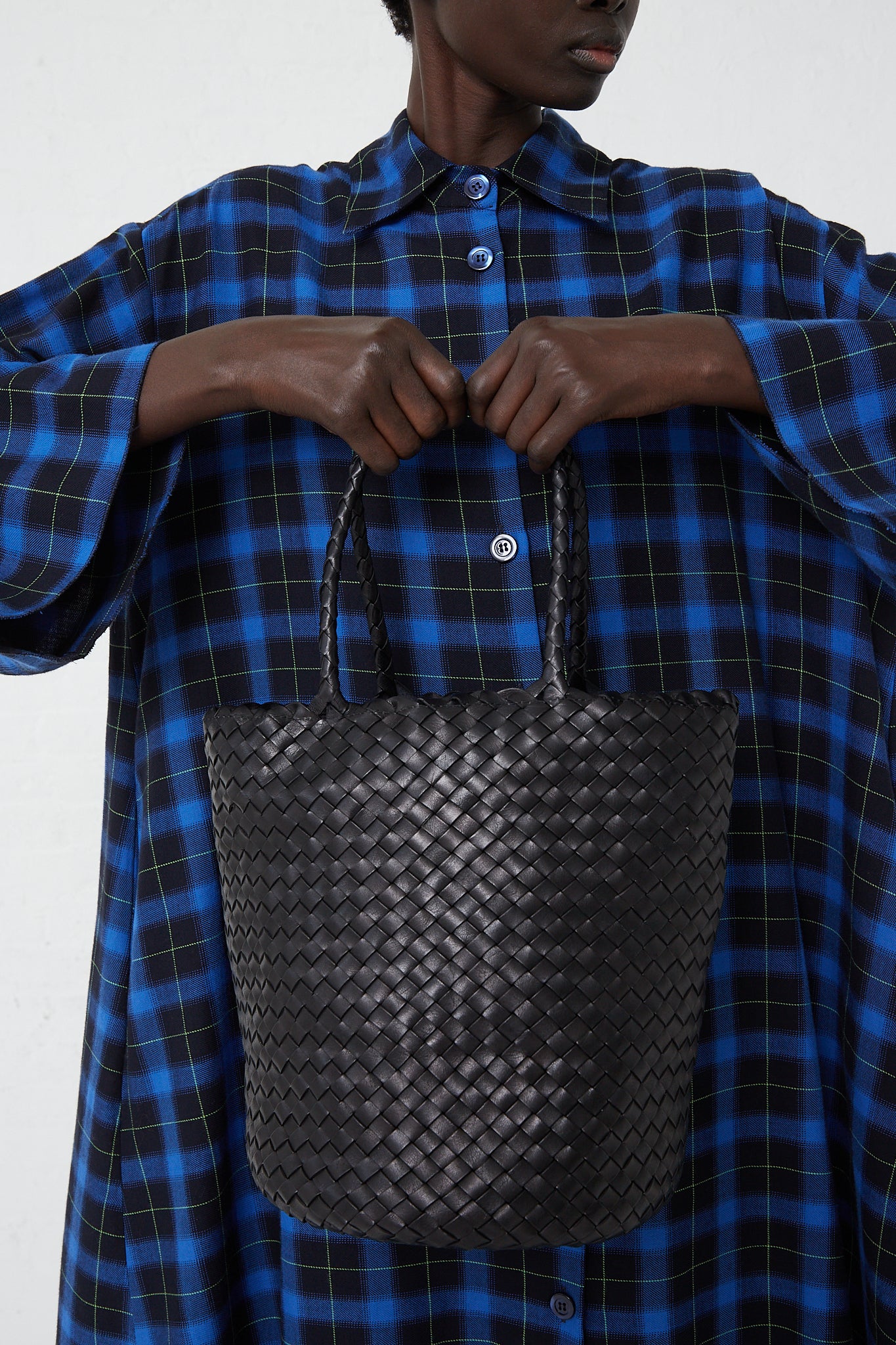 A woman in a plaid shirt holding a Dragon Diffusion Jacky Bucket Bag in Black.