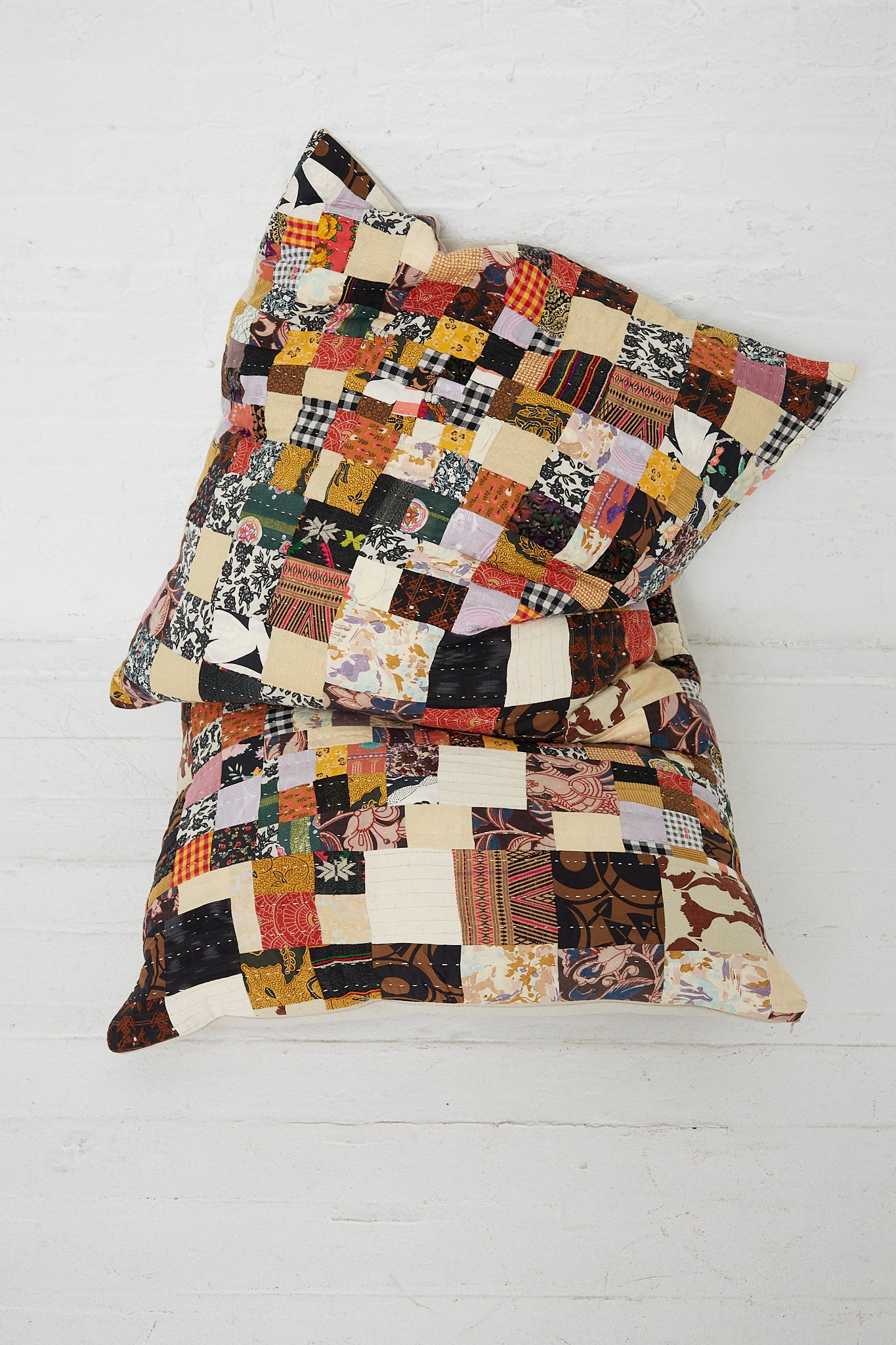 A pair of Counterpane Patchwork Pillows in Brown Multi II, showcasing an antique found cloth and embellished with freehand quilting style.