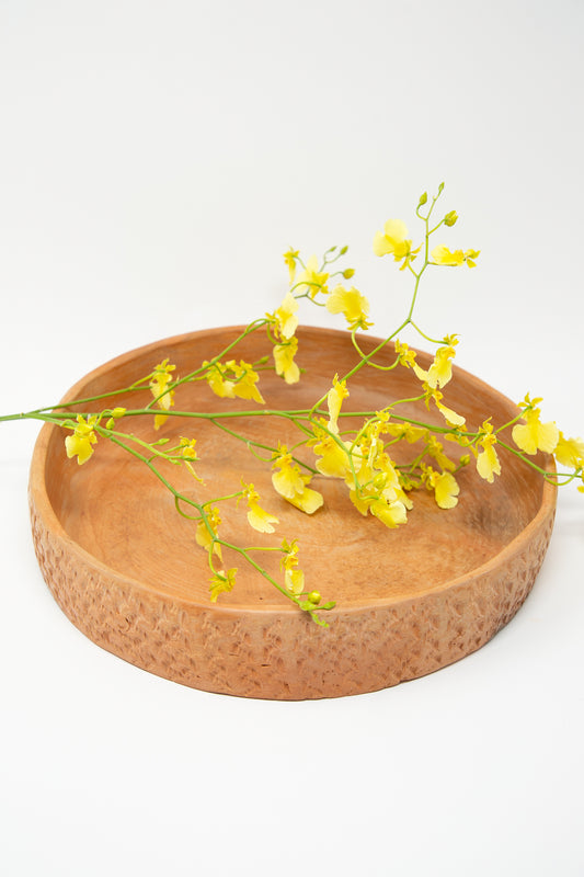 A rustic Julia Frutero Platter in Red Clay, adorned with yellow flowers, handcrafted by Cerámicas Plaza Bolivar.
